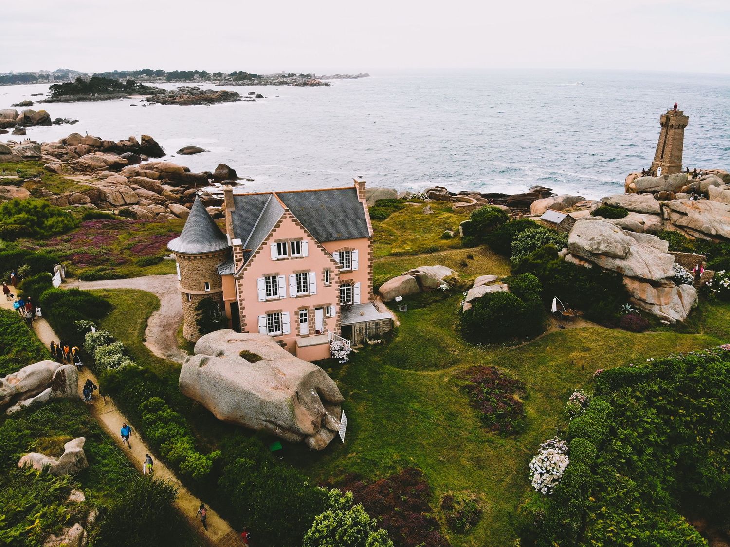 Photo au drone d'un batiment sur la cote bretonne avec le phare de ploumanac'h en fond