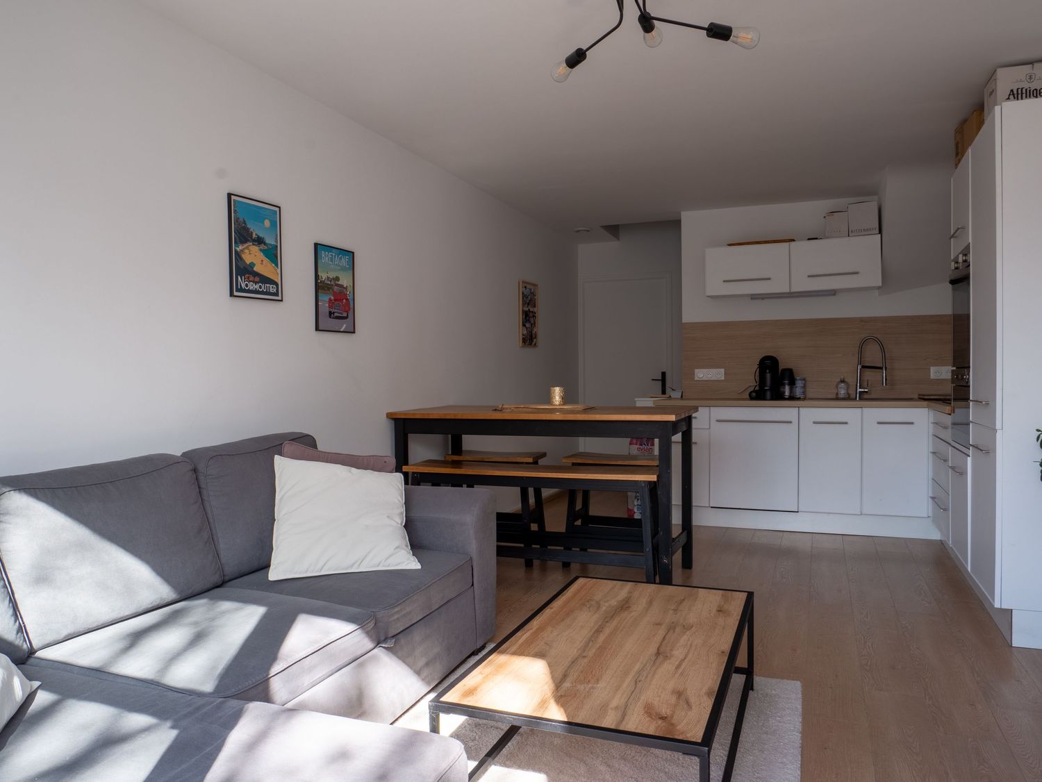 Photo immobilière d'un salon de duplex lumineux on y voit la cuisine en fond et le salon en premier plan