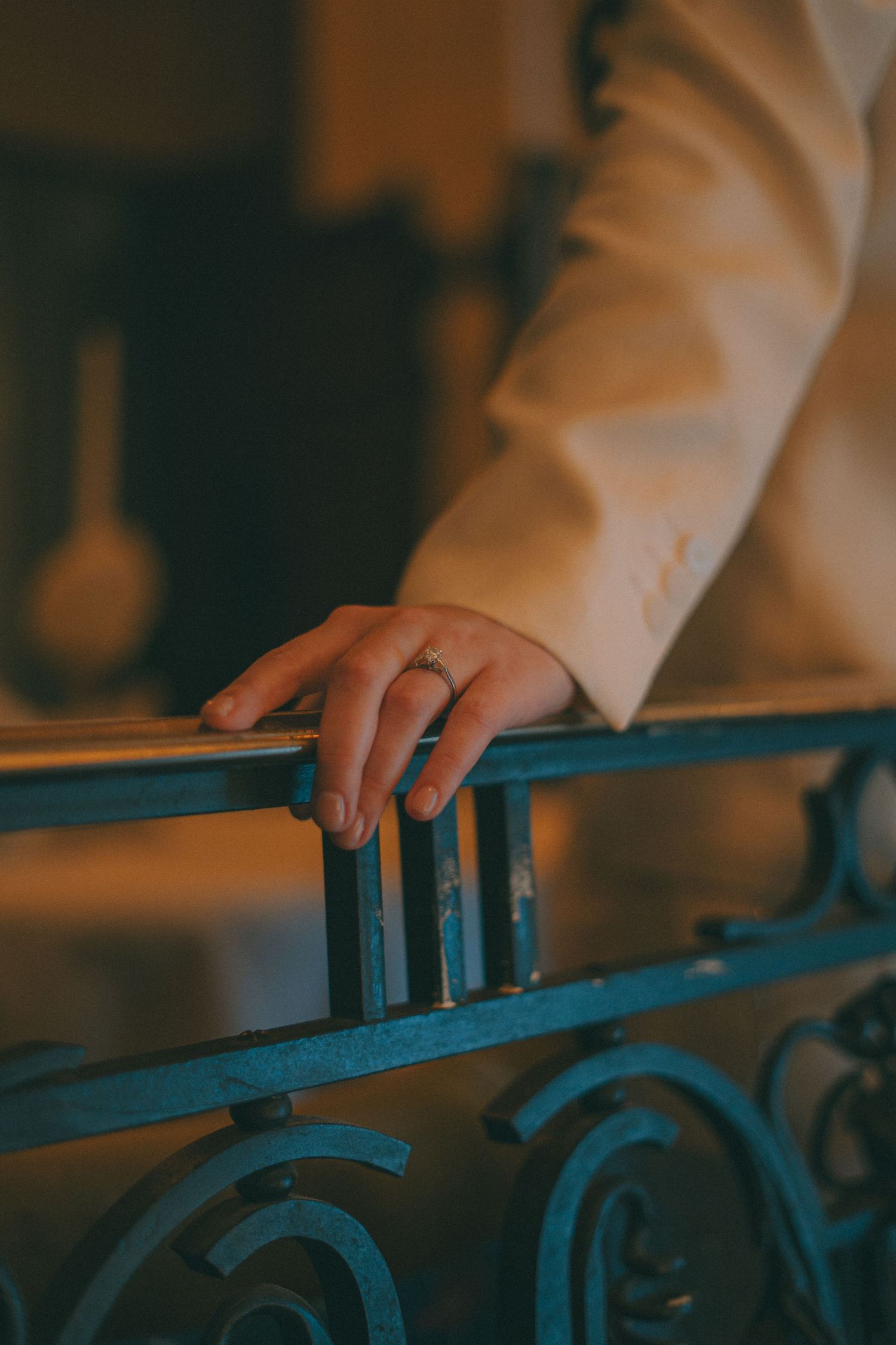 Main d'une marié posée sur une rembarde avec un focus sur sa bague de mariage
