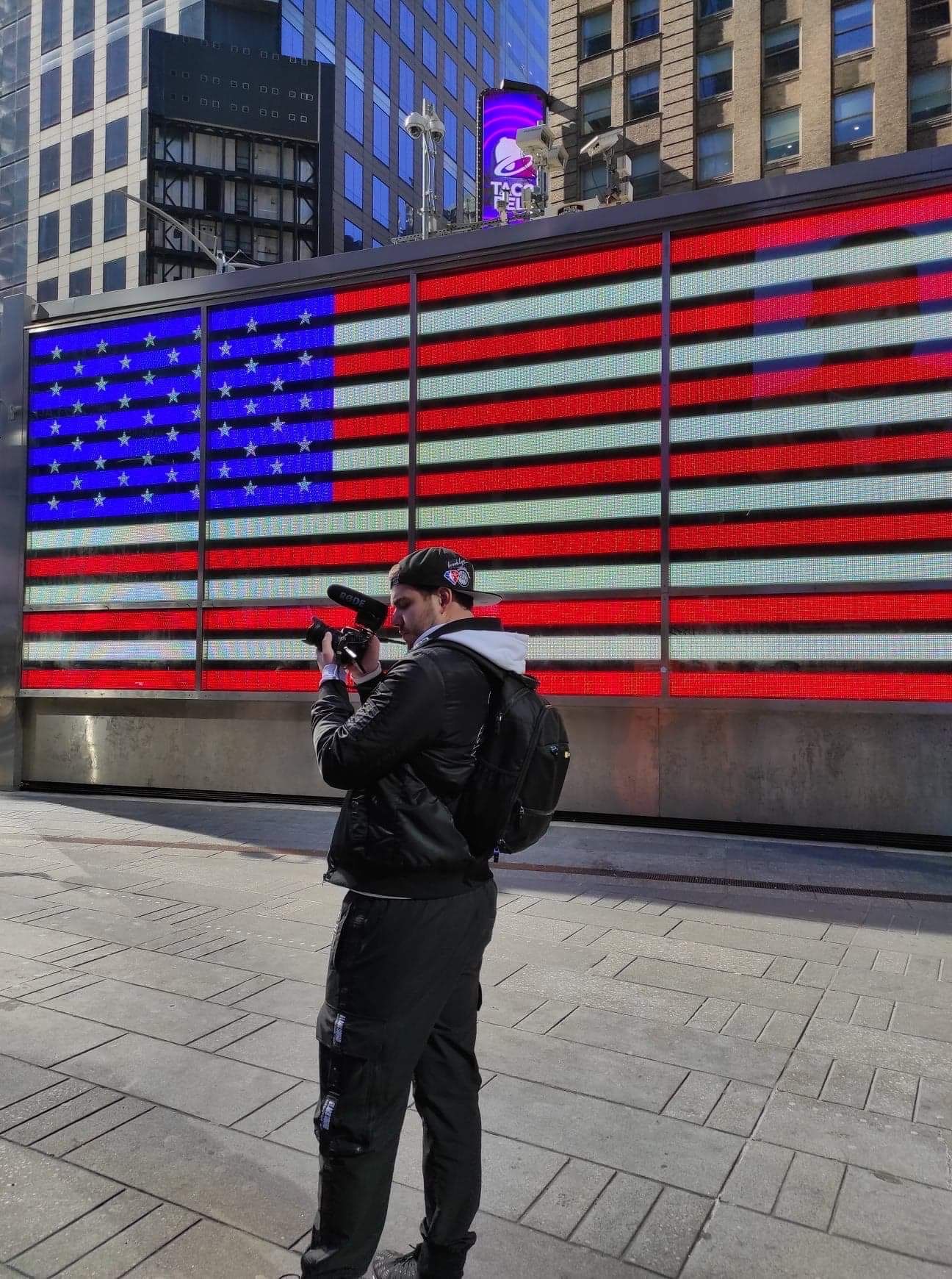 Photo de moi prenant du contenu a New York devant un ecran LED projettant le drapeau américain