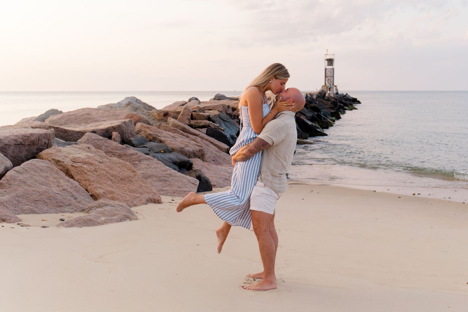 A couple kissing at a scenic Montauk beach while celebrating their engagement proposal with a photoshoot