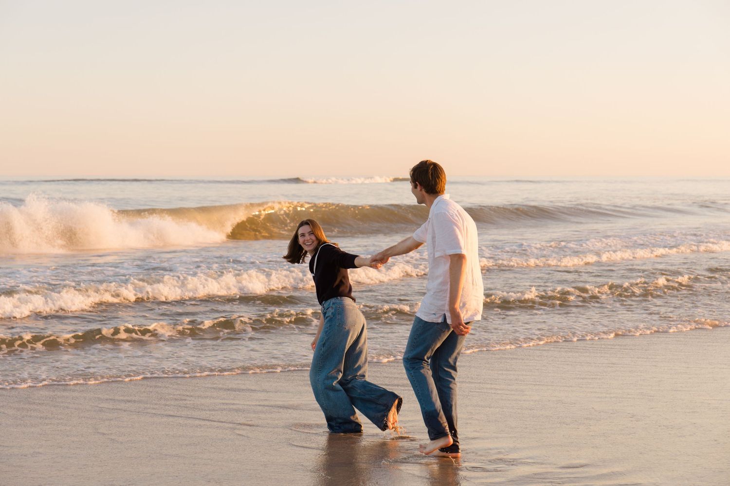 A couple dances together on a beach in Westhampton at sunset as waves crash behind them on the shoreline for a Hamptons photographer capture