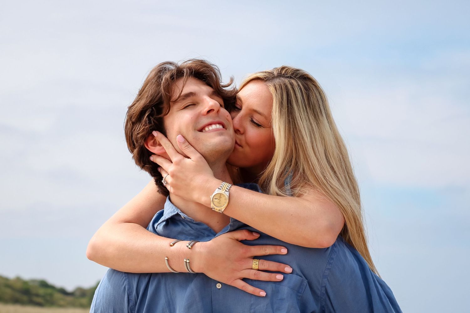 A romantic couple embraces on a Hamptons beach during sunset wearing casual attire and celebrate their engagement with a proposal photoshoot