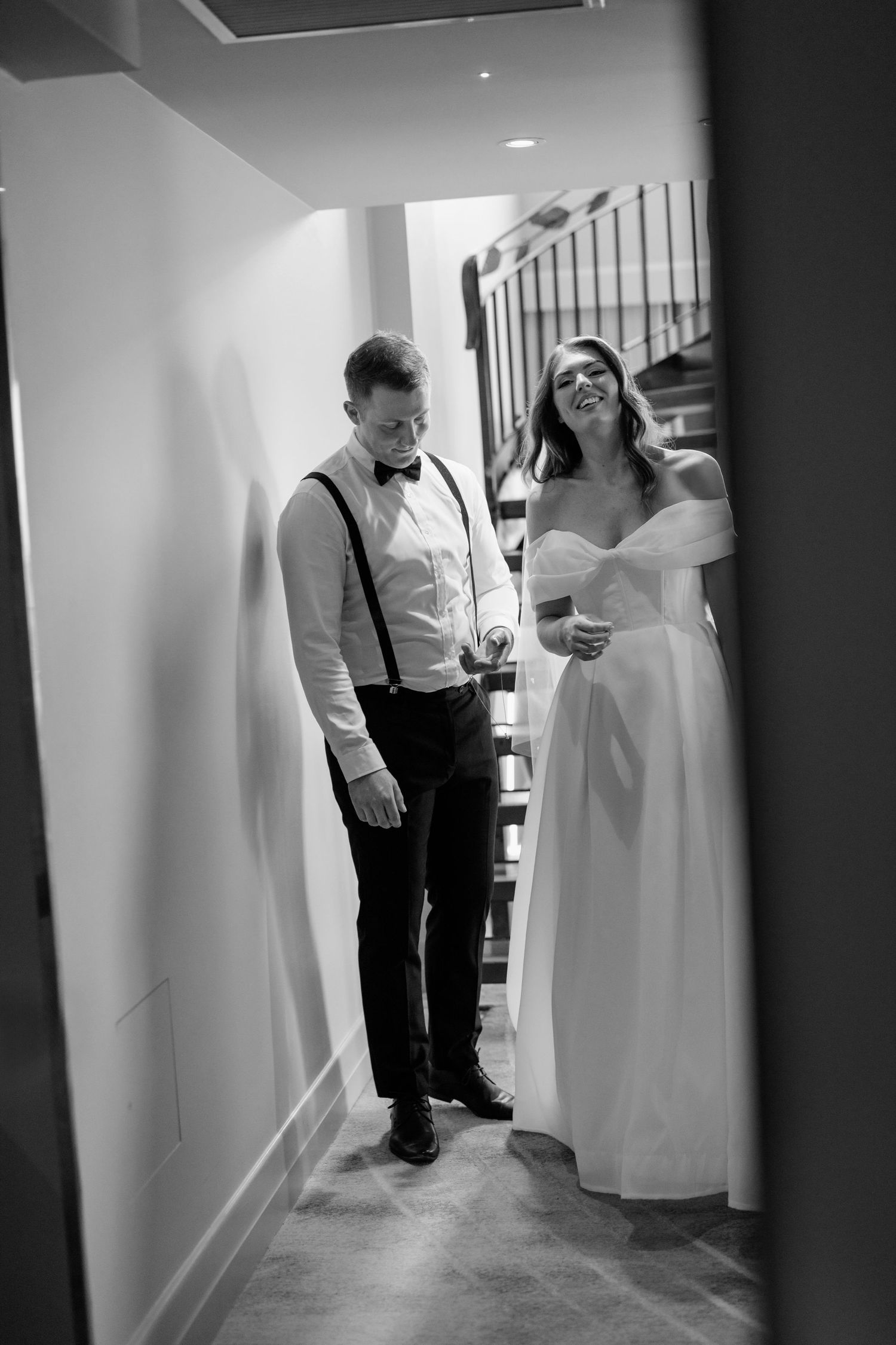 Black and white wedding photograph series showing a couple in a hallway with the bride in white dress and groom in suspenders.