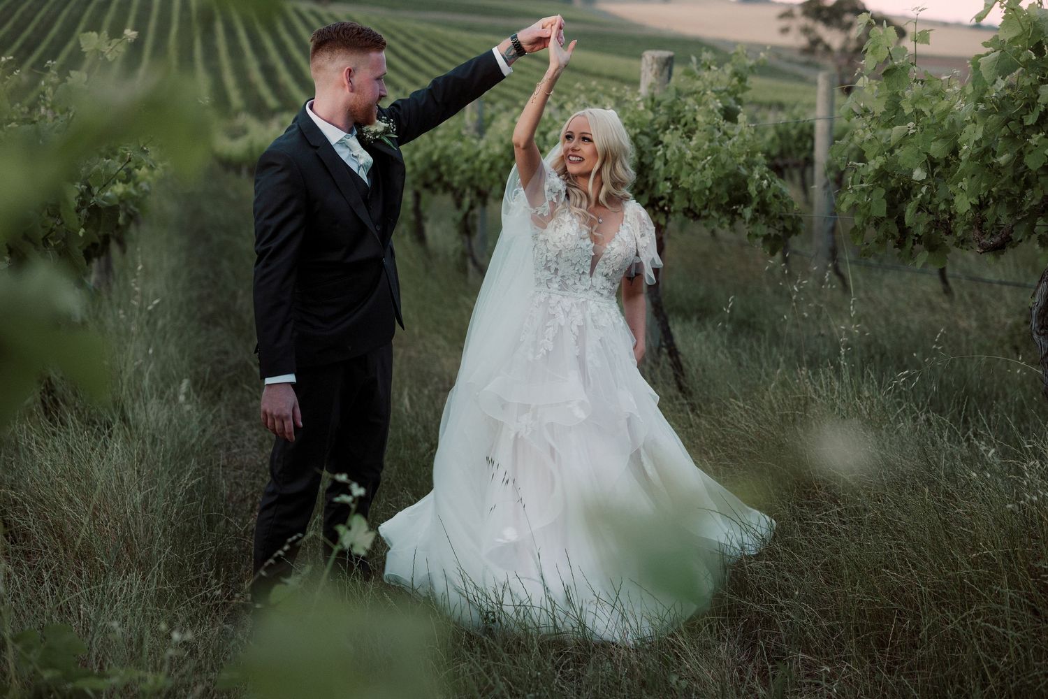 A couple shares a romantic moment in a lush vineyard setting during their wedding photoshoot.