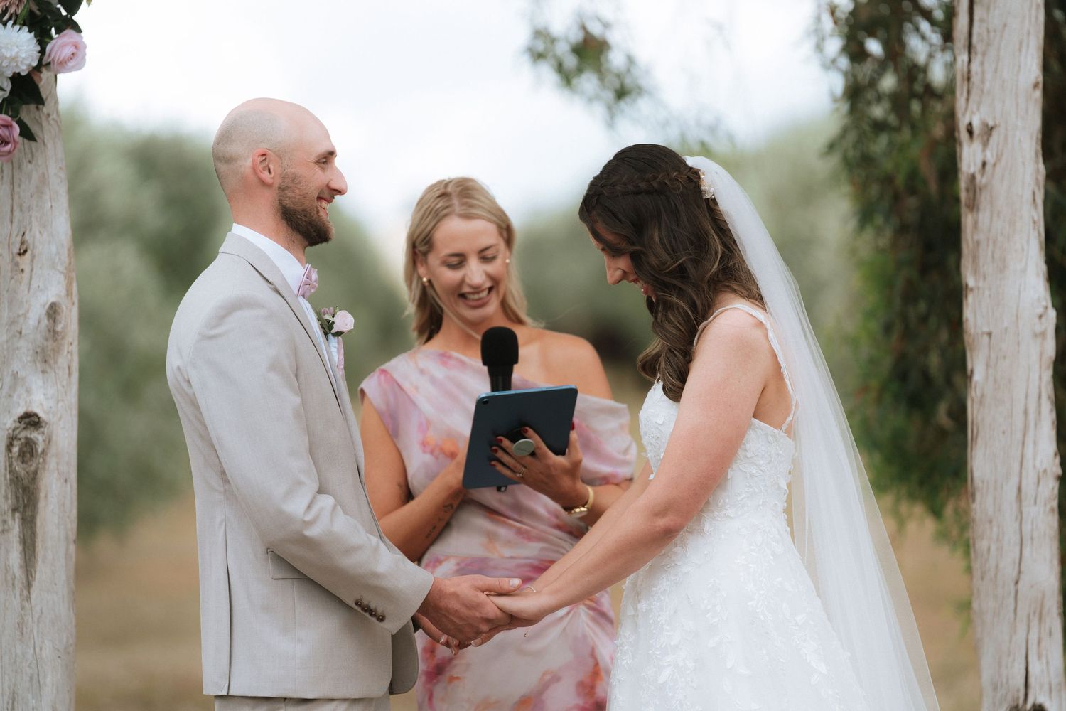 Wedding guests share emotional embraces during an outdoor celebration in a rustic setting.