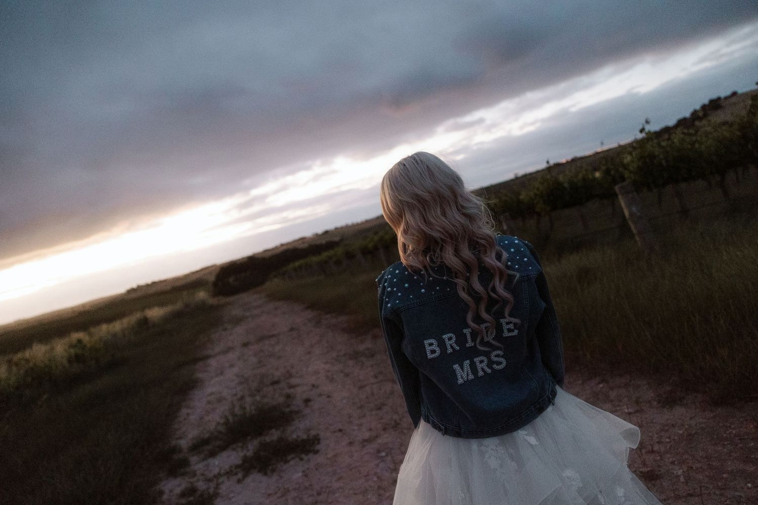 Denim jackets with custom embroidery photographed against sunset sky.
