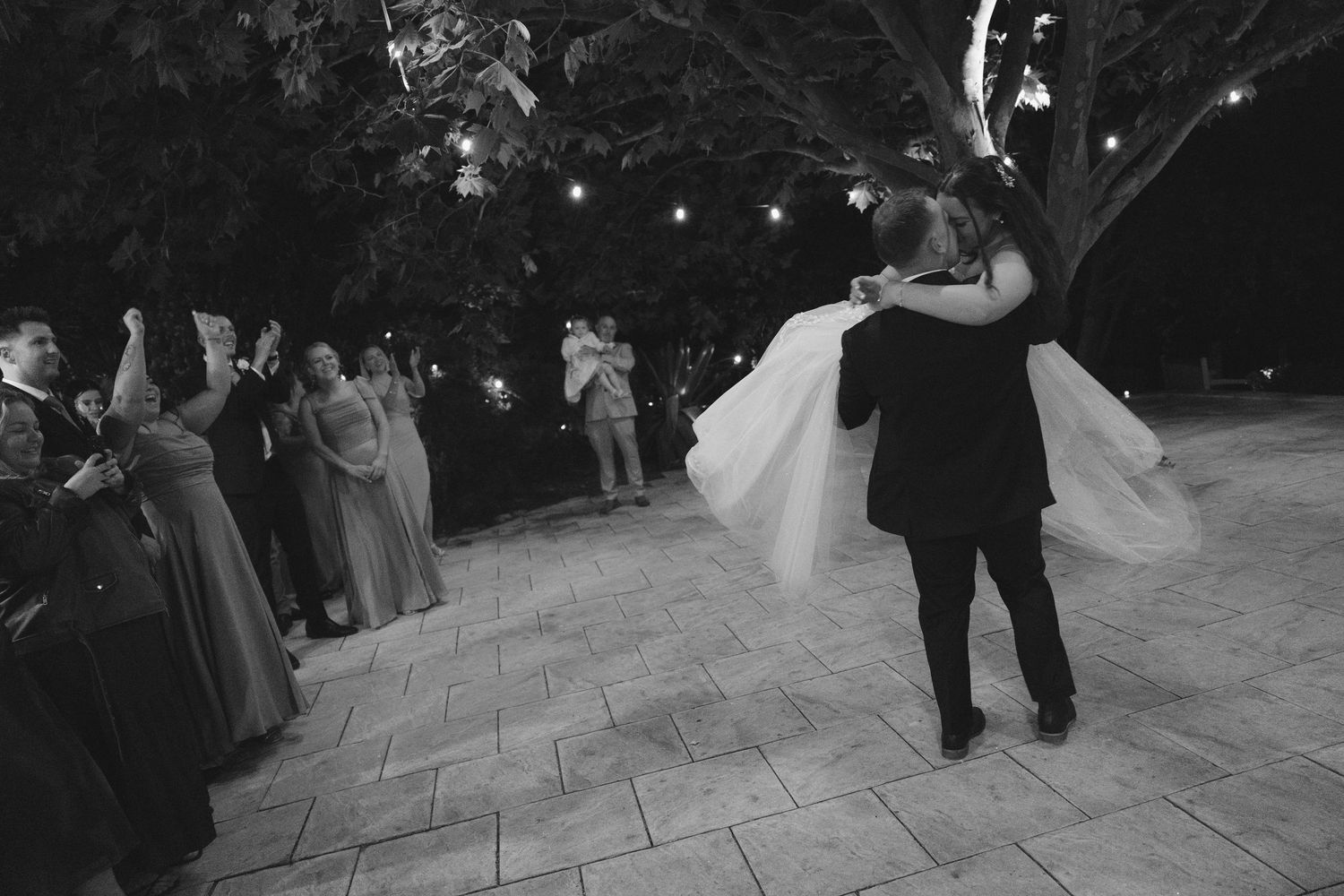 A couple dances together during a romantic first dance at an outdoor wedding reception.