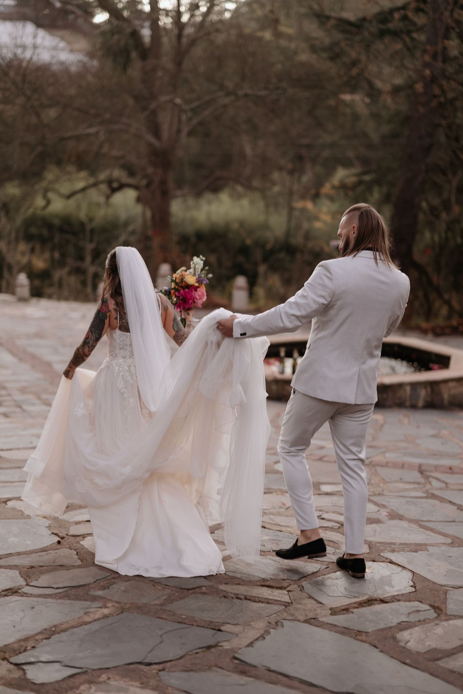 A sequence of photos showing a bride in a flowing white dress and someone in a suit playfully dancing on stone pavement.