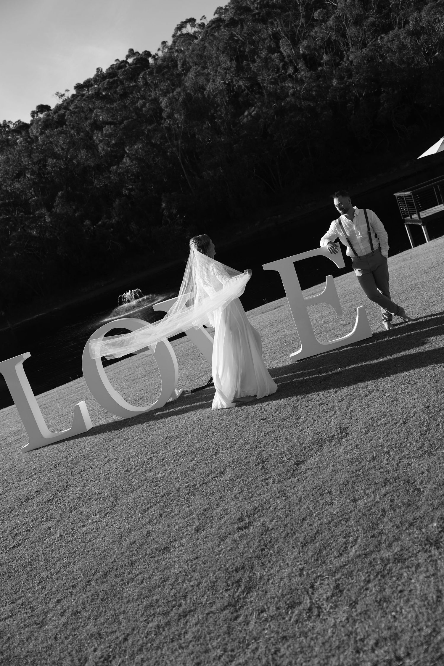 A black and white artistic sequence shows a flowing wedding dress moving across a grassy field.