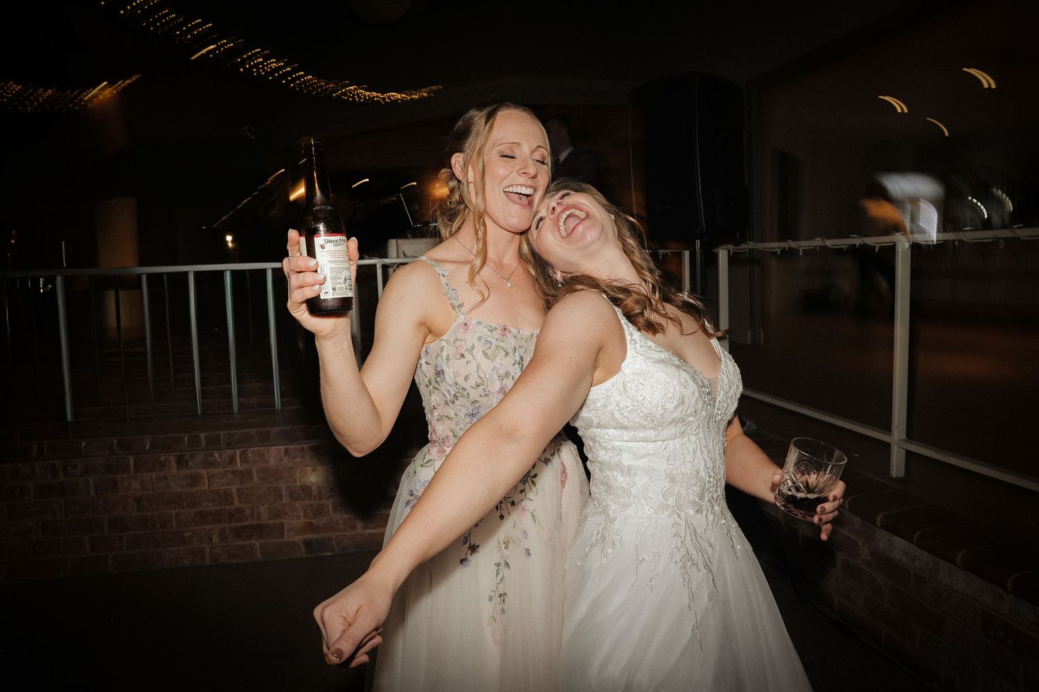 A bride in a white wedding dress dances joyfully during a wedding celebration at night.