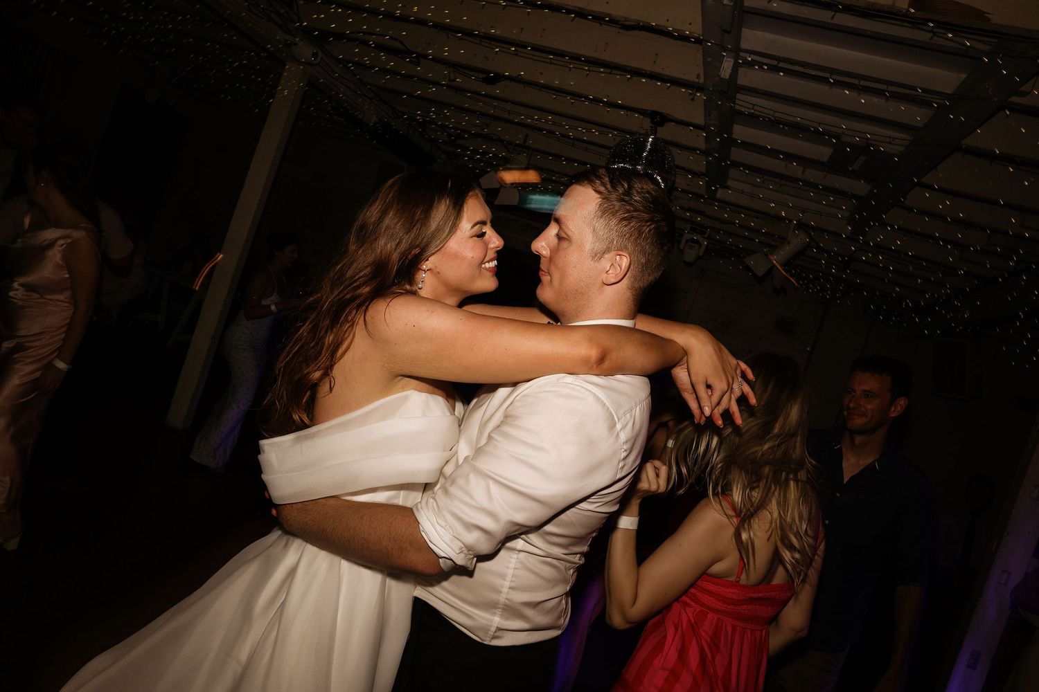 Couples dancing closely together at a dimly lit social dance event with romantic lighting and atmosphere.
