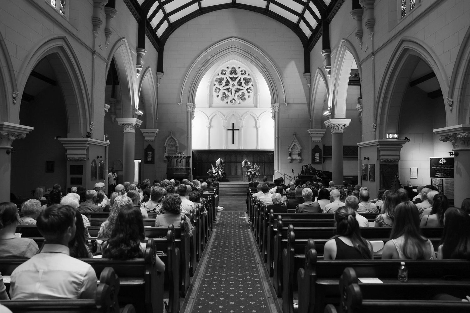 A panoramic sequence of black and white church interior photos showing pews, arches and stained glass windows during a service.