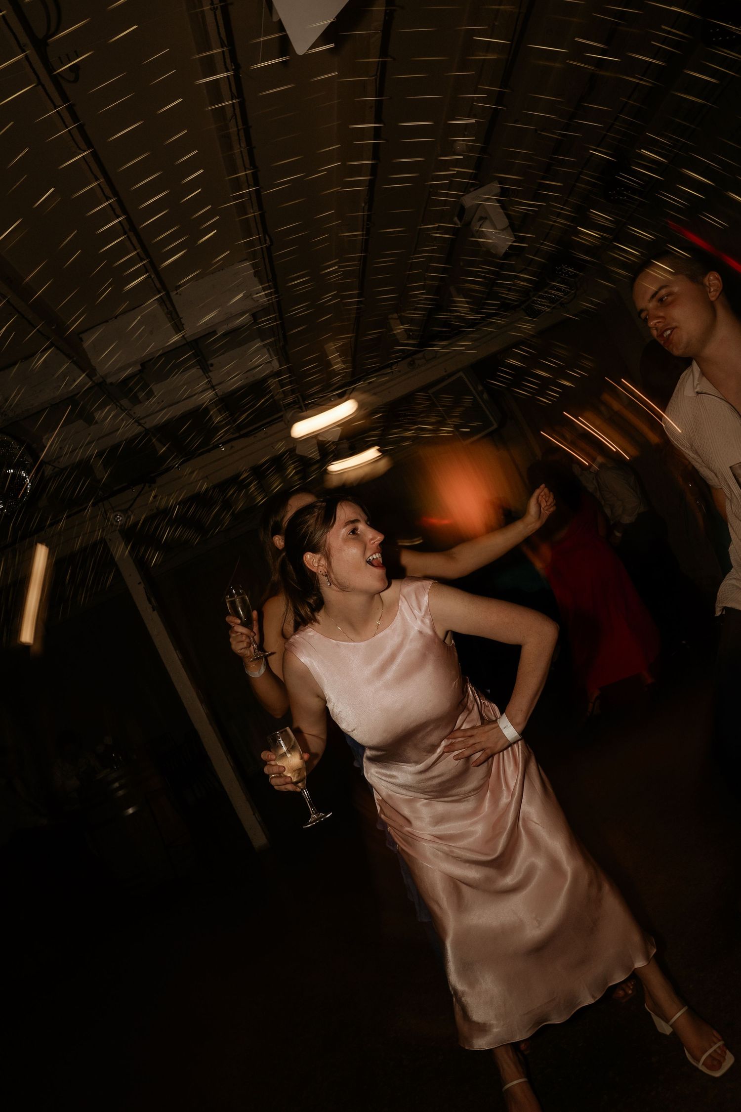 People dancing and celebrating in a dimly lit venue with dramatic lighting and movement.