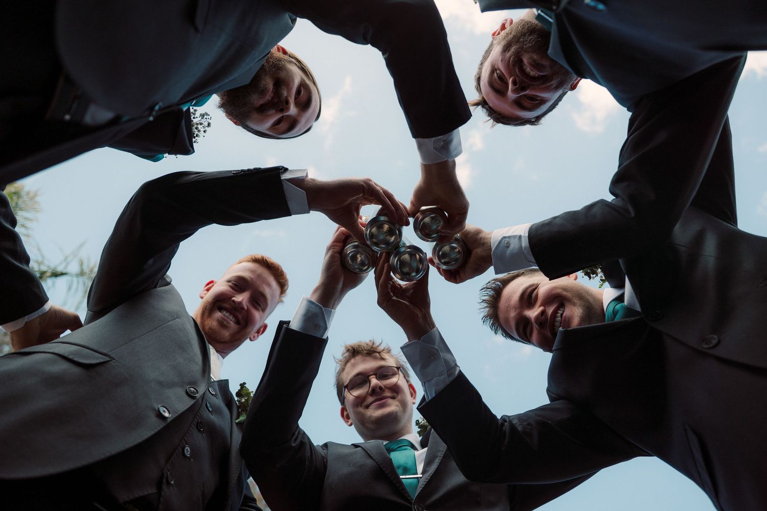 groom and best man  huddle together in a circle formation looking down at the camera from above. wedding photo ideas