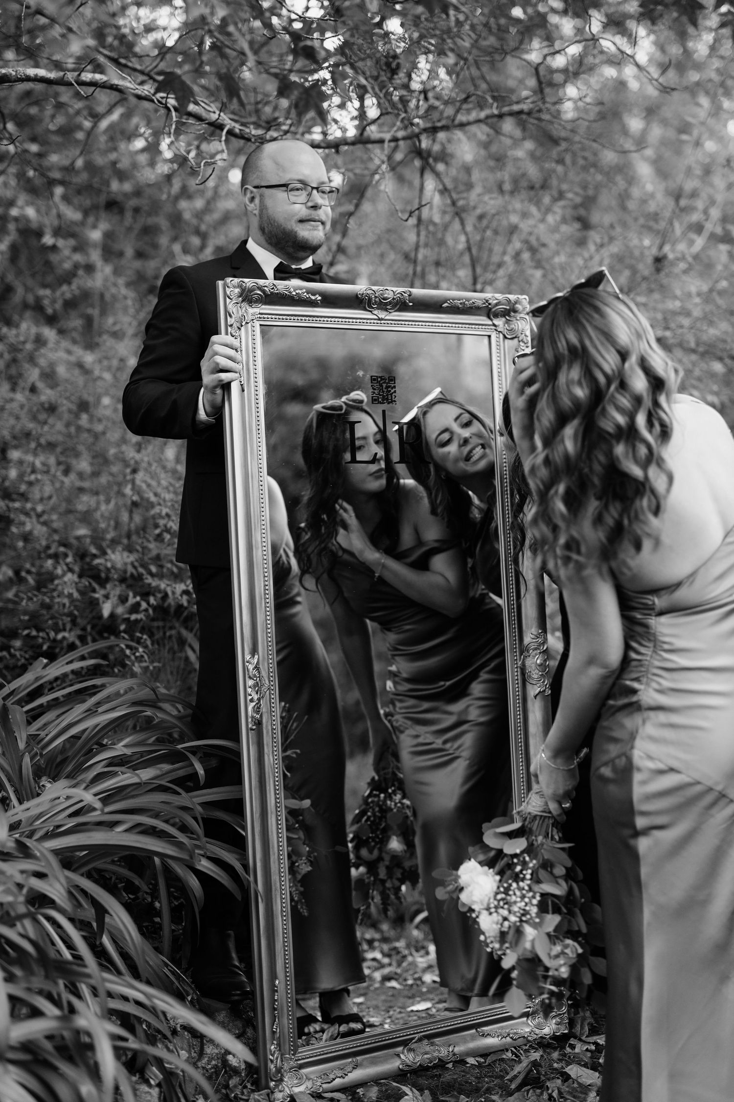 A couple poses with an ornate vintage mirror in a garden setting. wedding photography ideas
