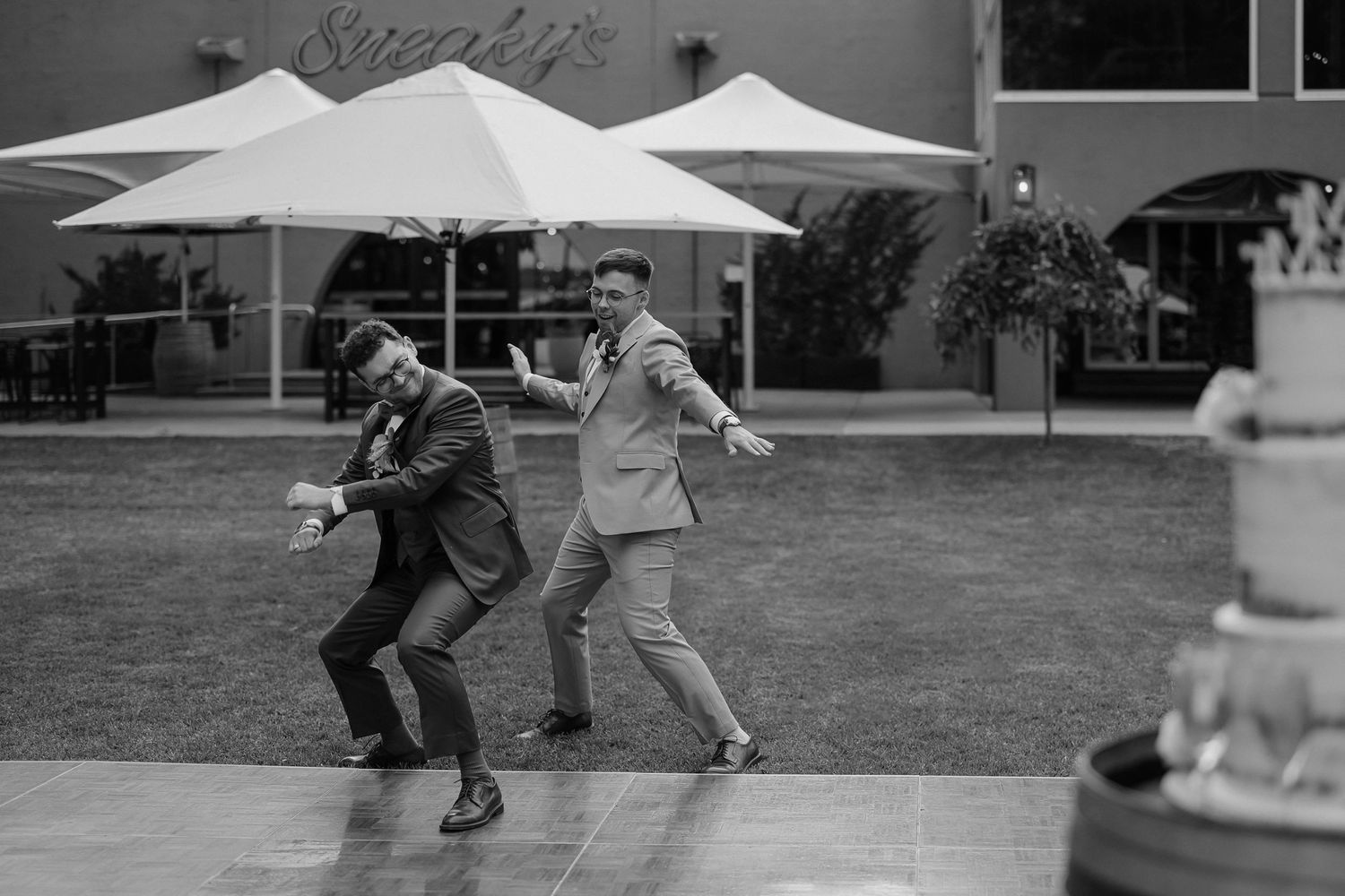Black and white image of people dancing and celebrating at an outdoor wedding reception.