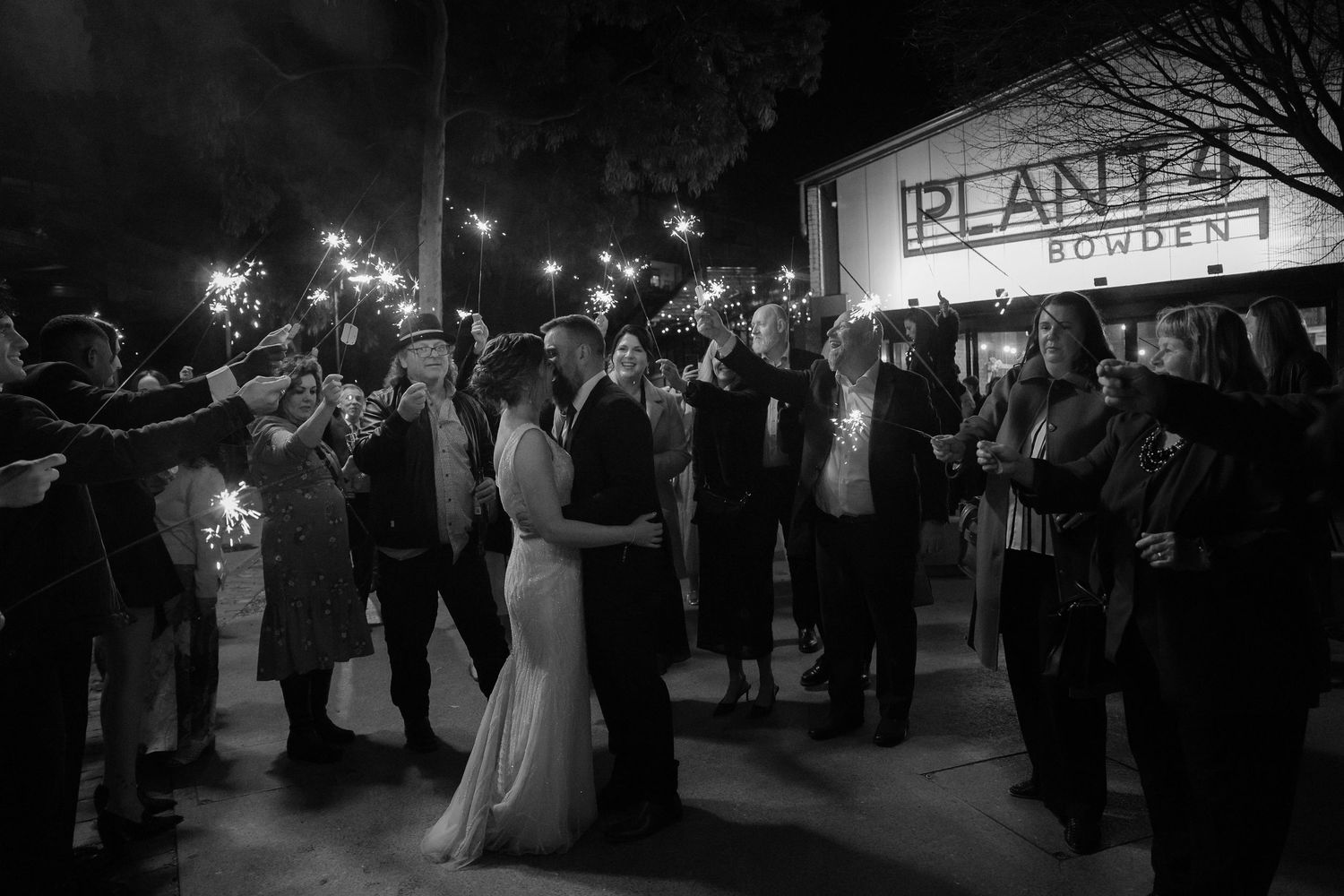 Wedding guests dance and celebrate on a dimly lit dance floor during an evening reception.