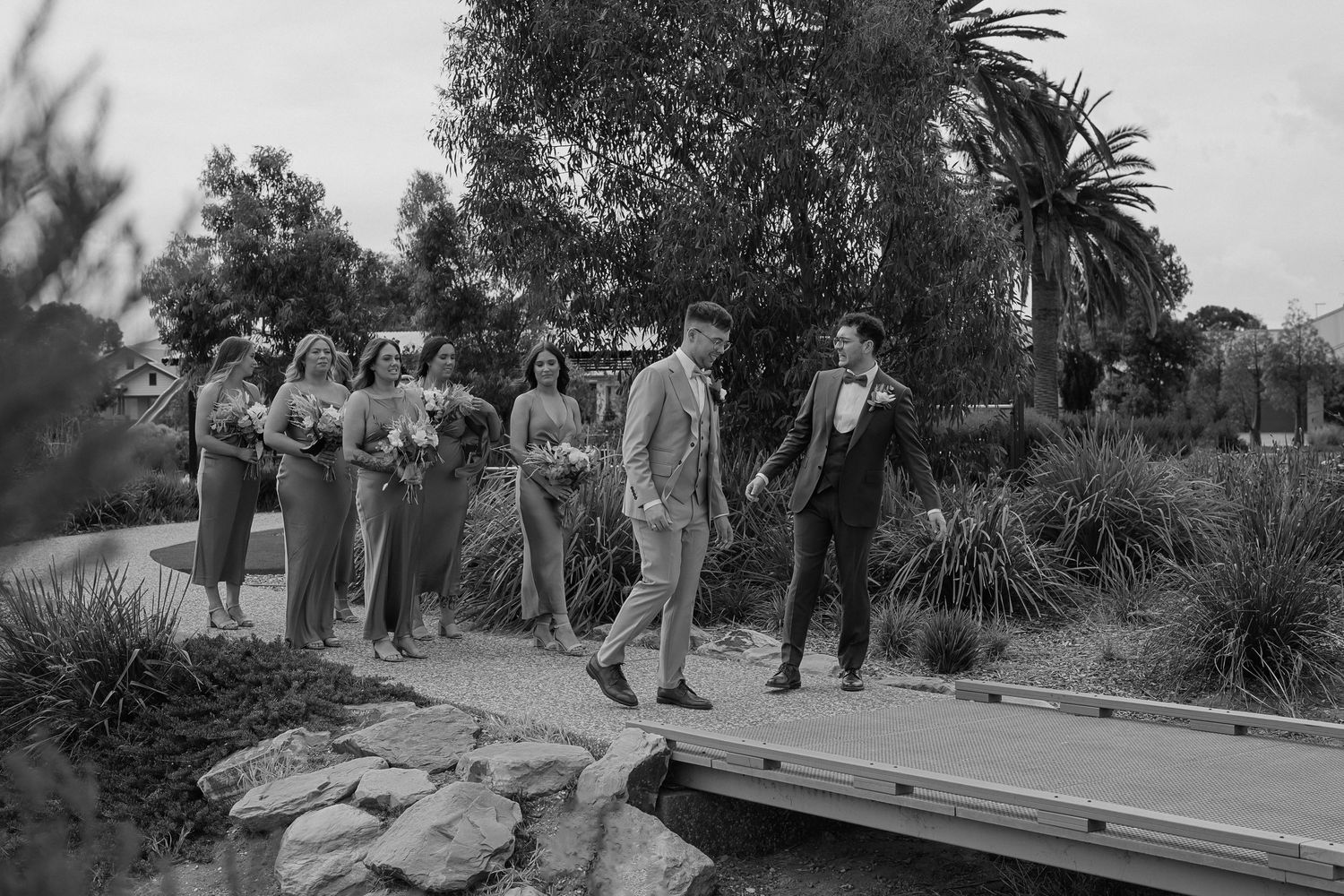 Black and white photograph of guests mingling at an outdoor wedding venue with palm trees.