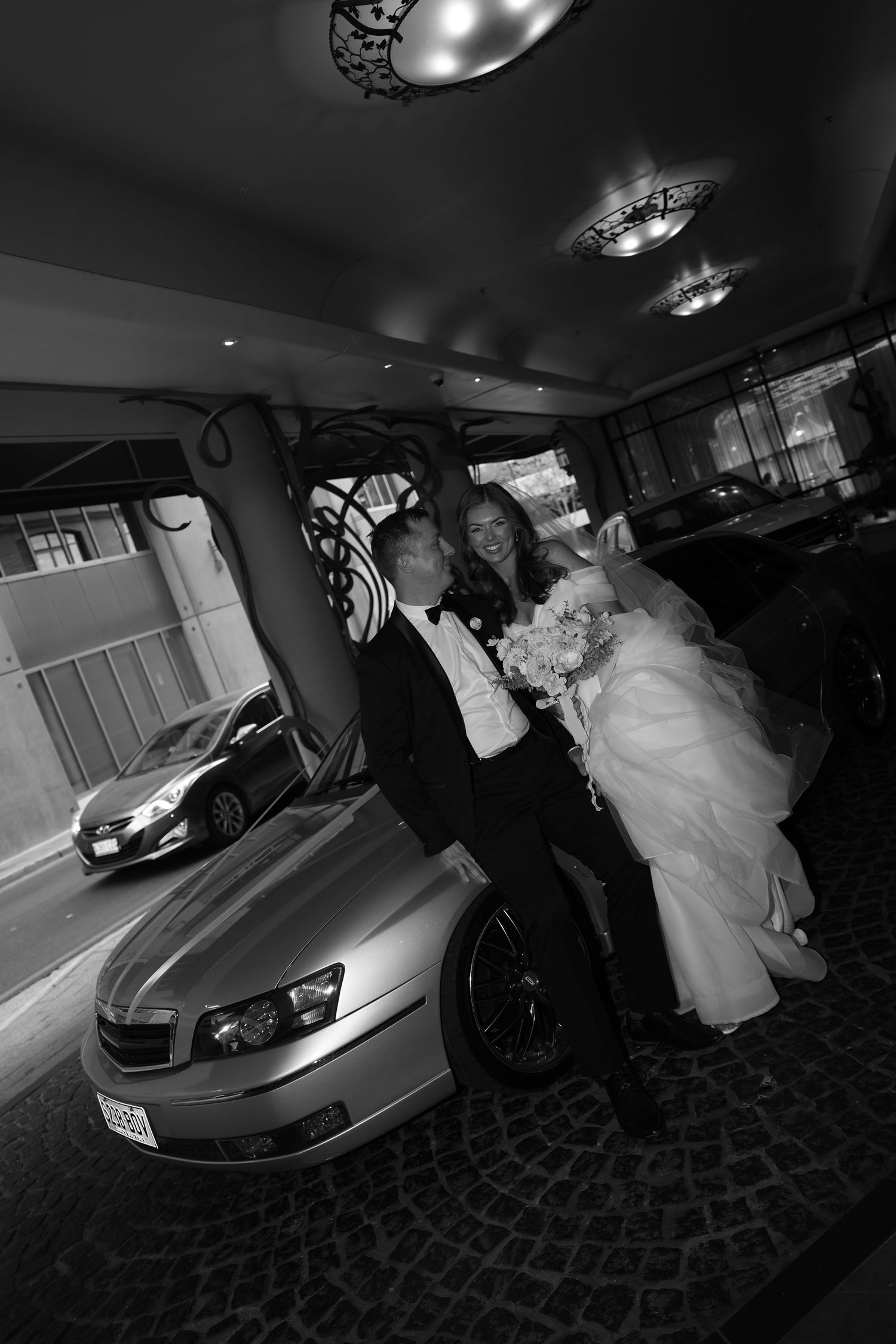 A series of black and white wedding photos showing a luxury sports car and bride in a flowing white dress.