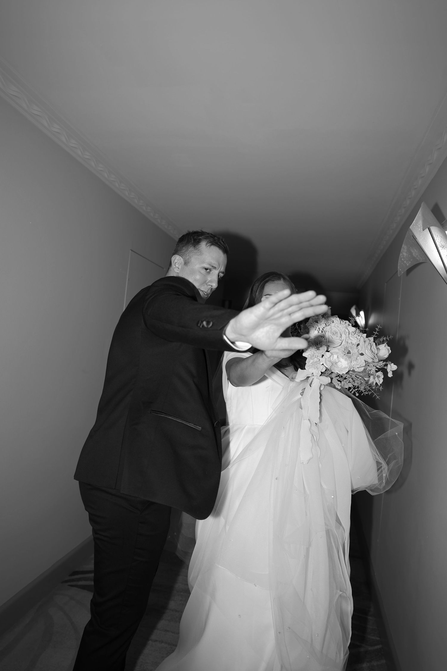 Dramatic black and white wedding photography in a narrow hallway.