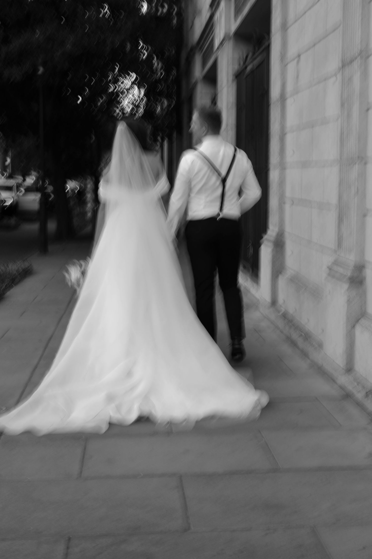 A blurred black and white image of a couple walking together on a stone pathway.