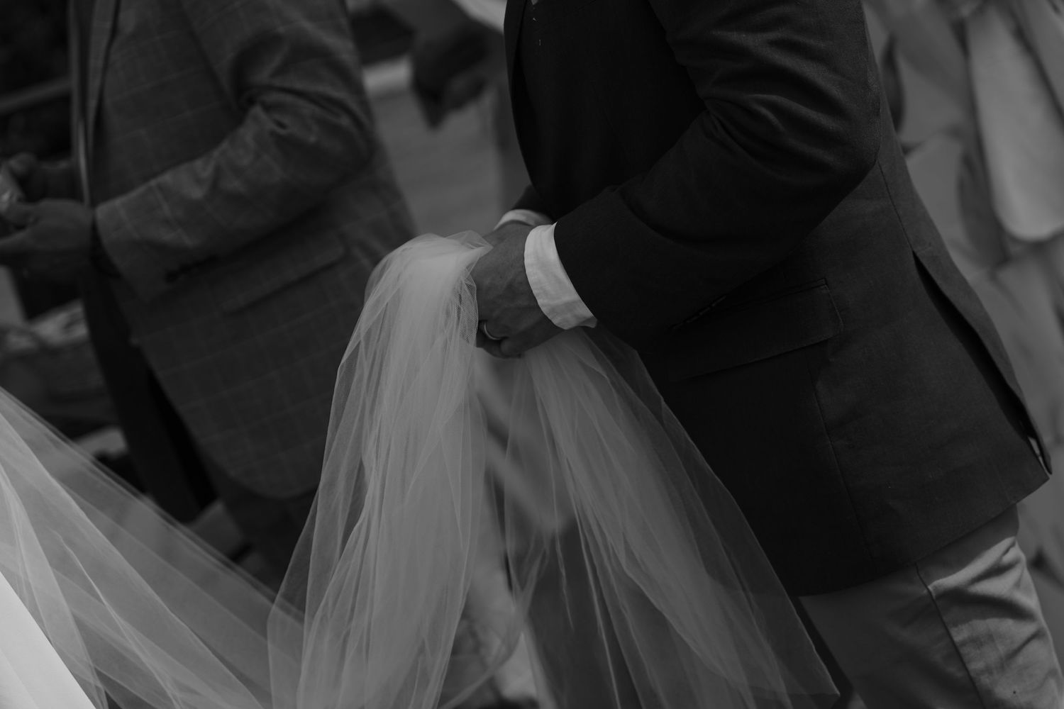 Black and white image of formal attire and flowing fabric creating elegant silhouettes at a gathering.