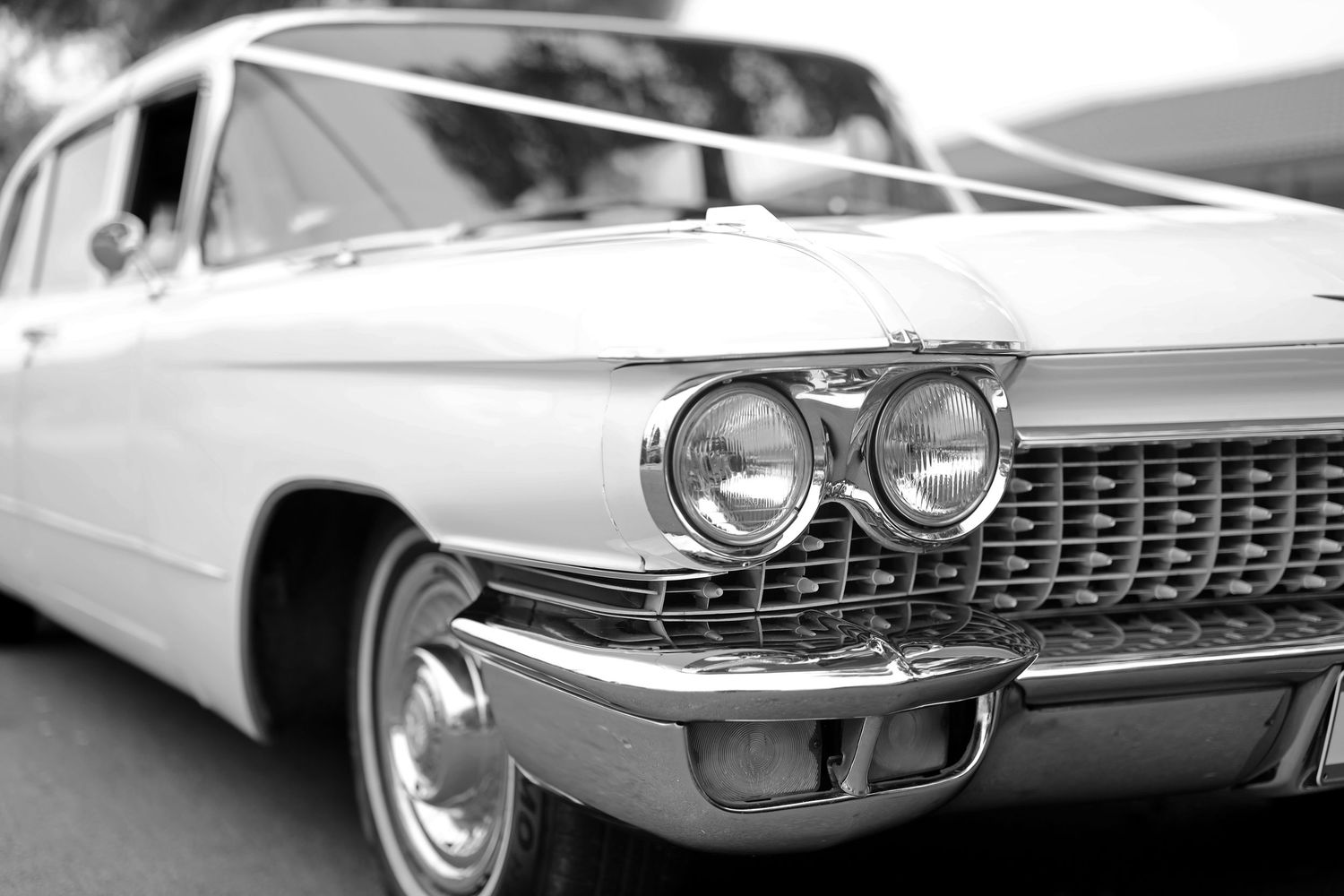 Classic vintage car headlights and chrome grille details shown in black and white photography.