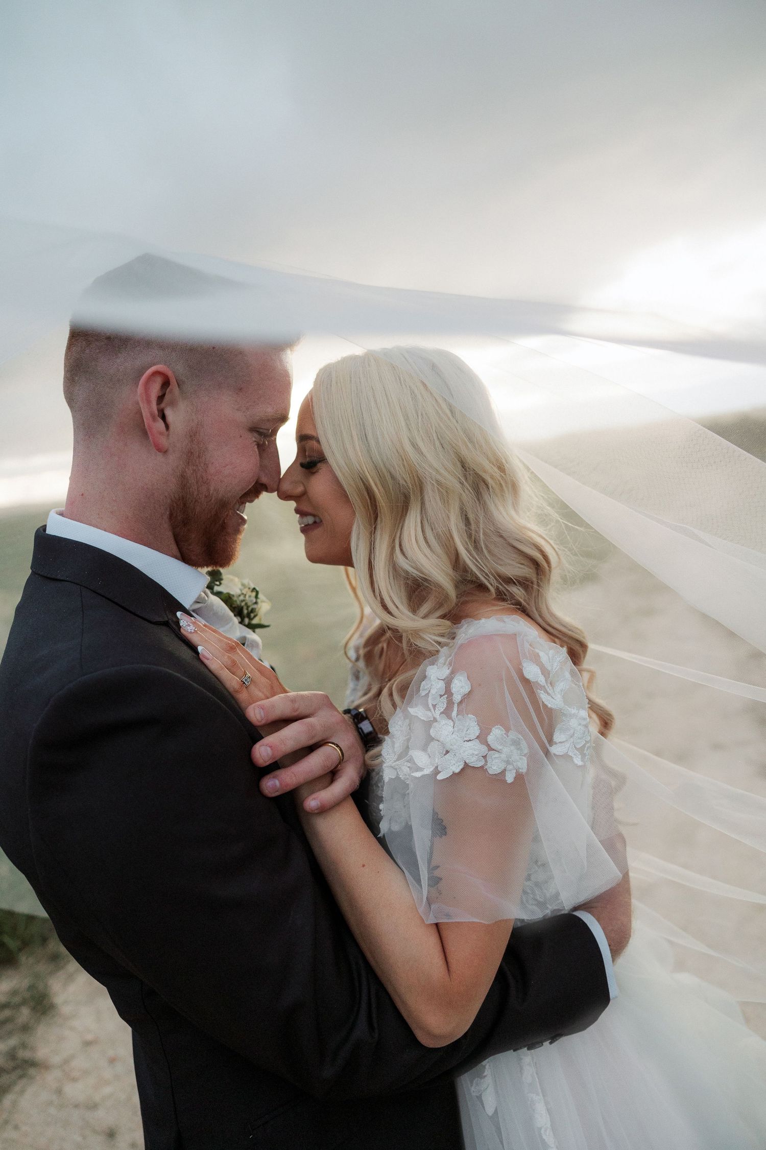 A romantic wedding portrait sequence showing a couple embracing as a veil flows in the wind at sunset.