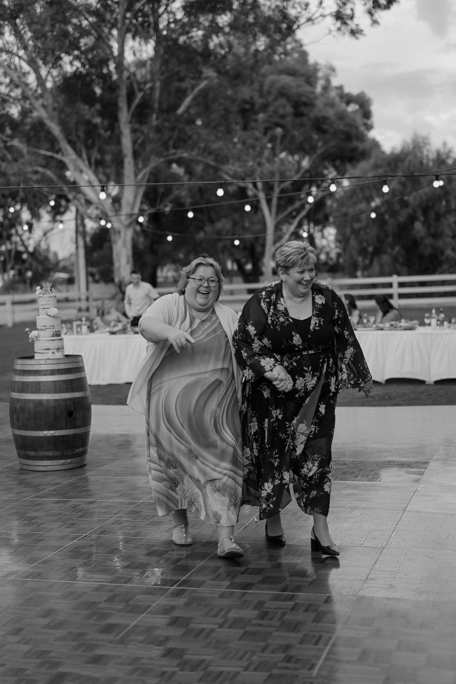 A sequence of black and white photos showing people dancing together on an outdoor patio with string lights and wine barrels.