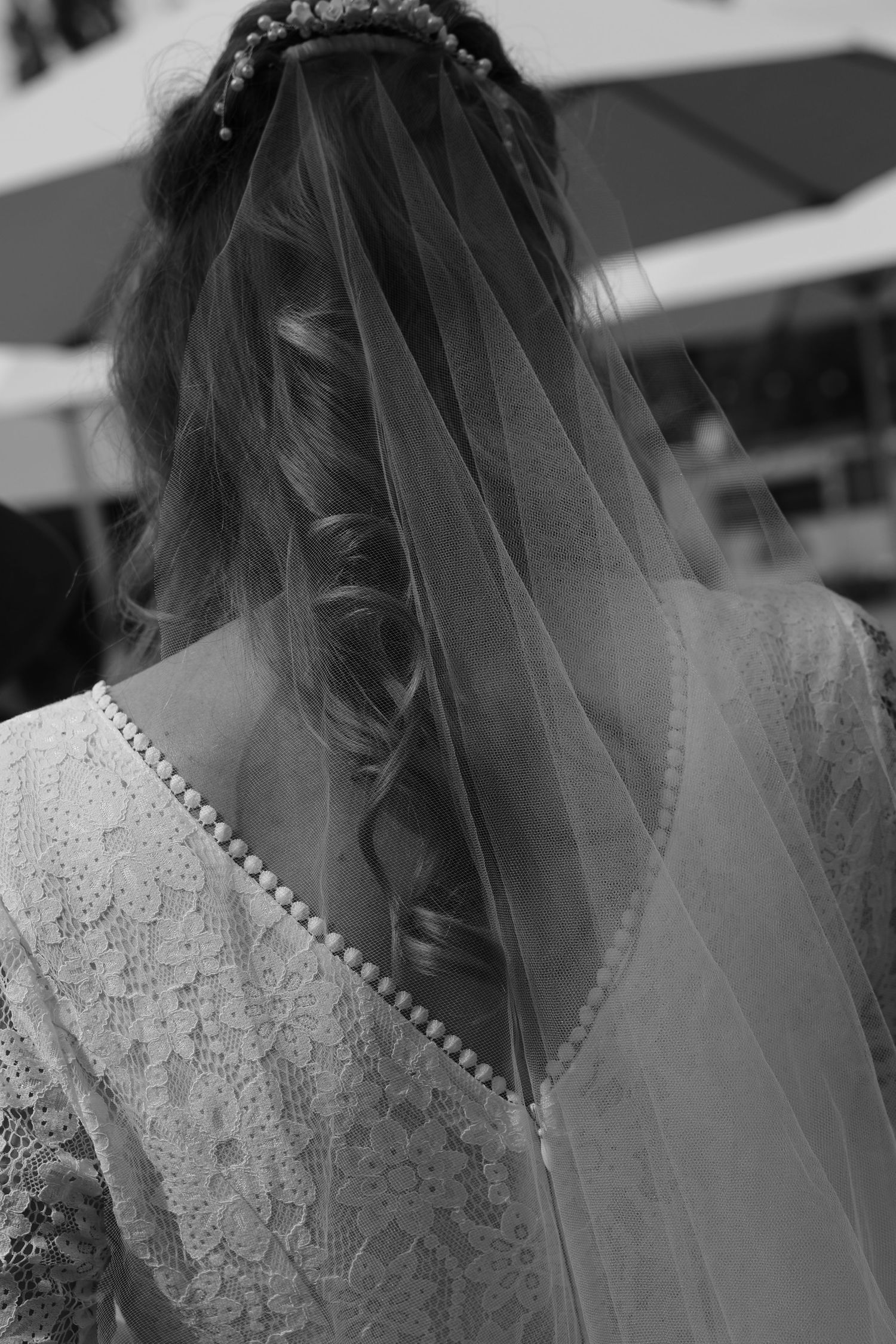 Close-up detail of a bride wearing a delicate lace wedding dress and veil with pearl accents.