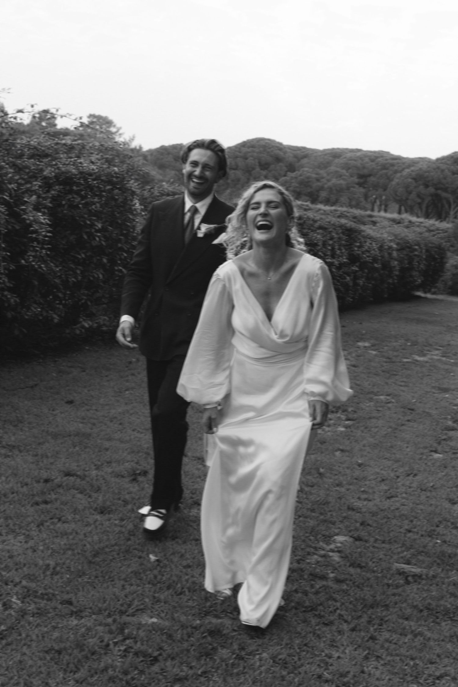 Joyful candid moments captured in black and white as figures dance in a grassy field.