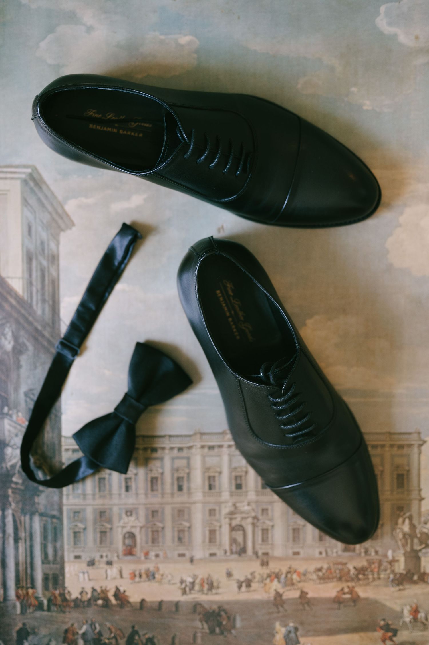 Black dress shoes arranged artistically on an antique architectural print background.