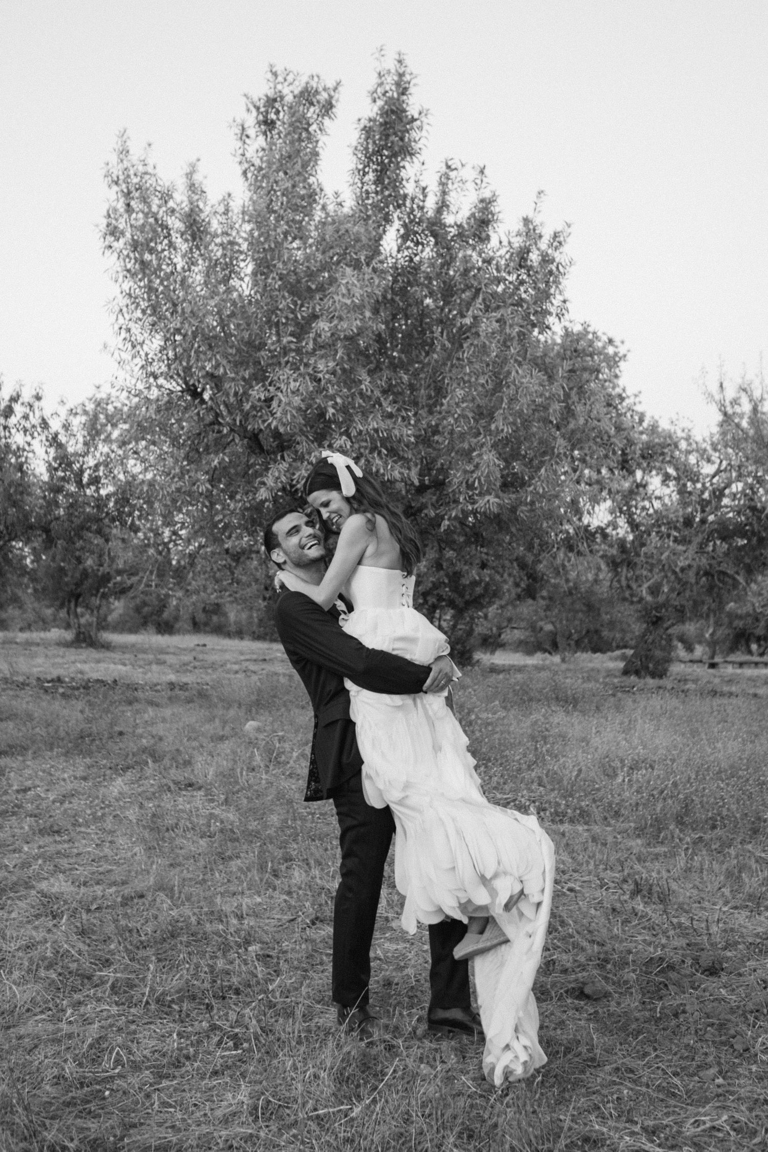 A romantic dance sequence captured in black and white photography among olive trees.