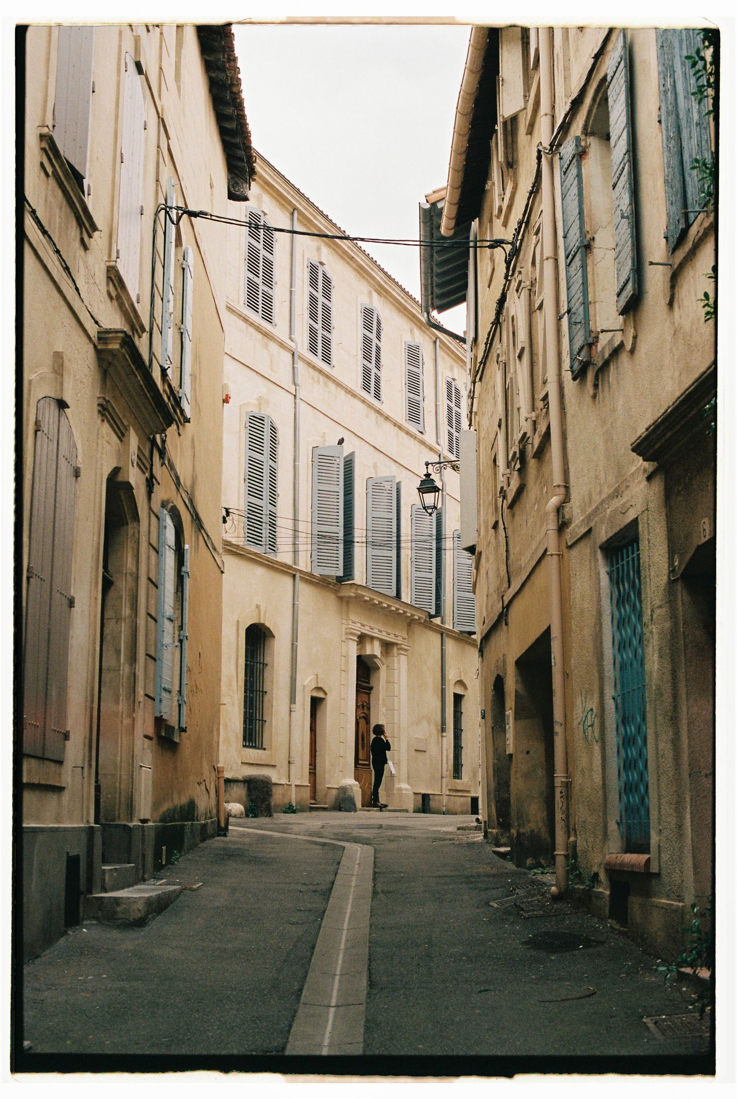 Narrow cobblestone street lined with traditional European buildings and shuttered windows.