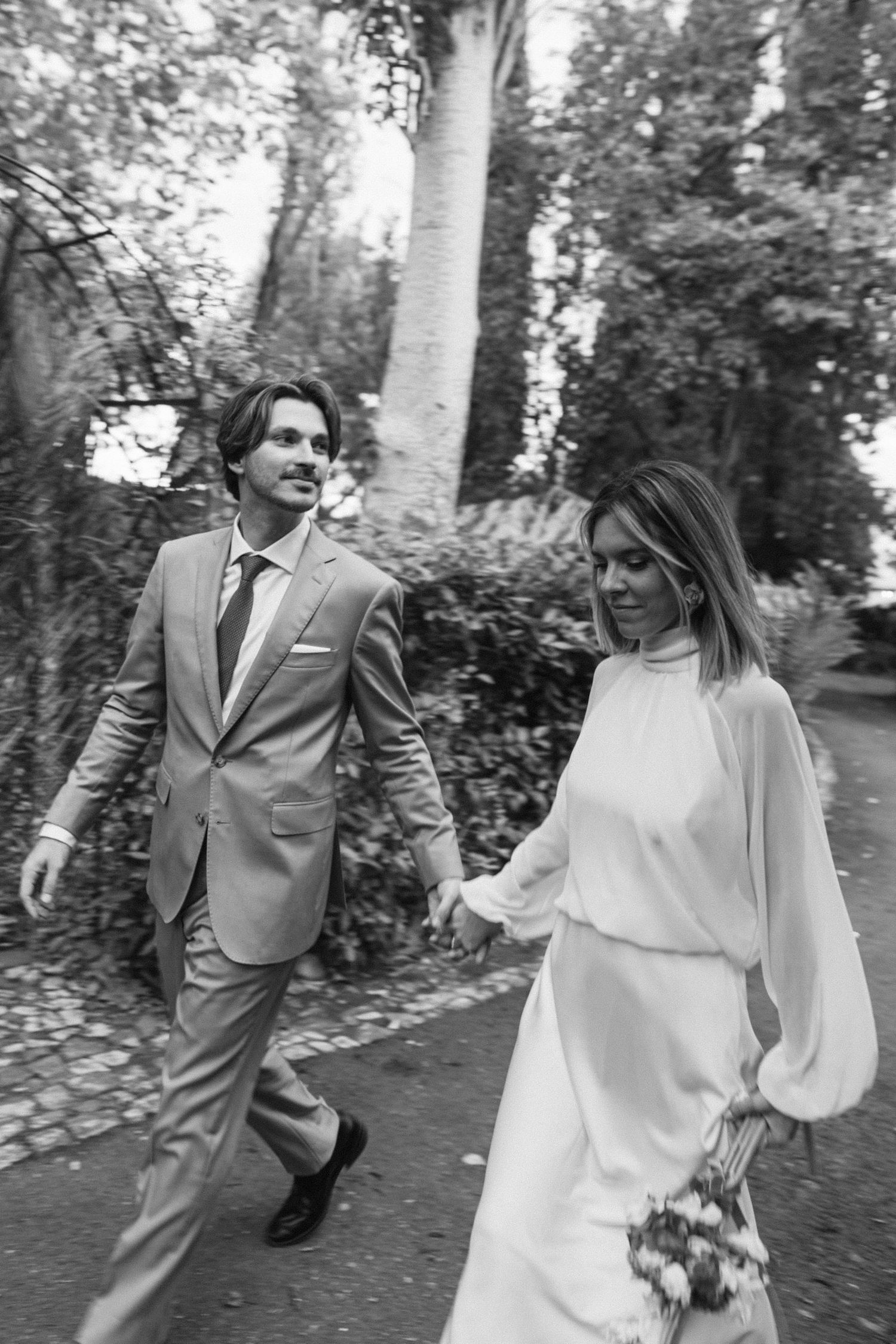 Black and white wedding photography capturing joyful moments in a garden setting.