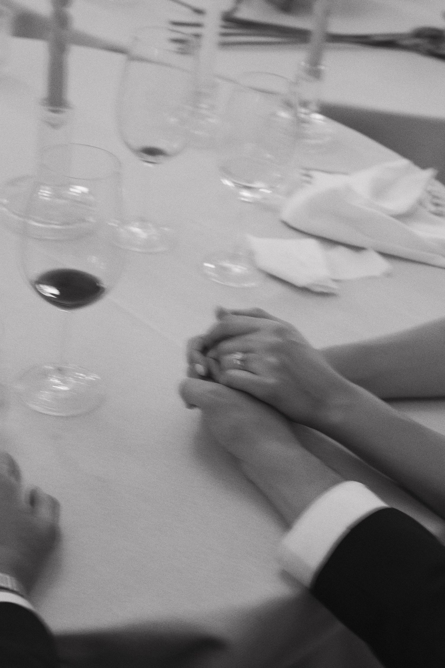 Hands reaching across a formal dining table set with white linens.