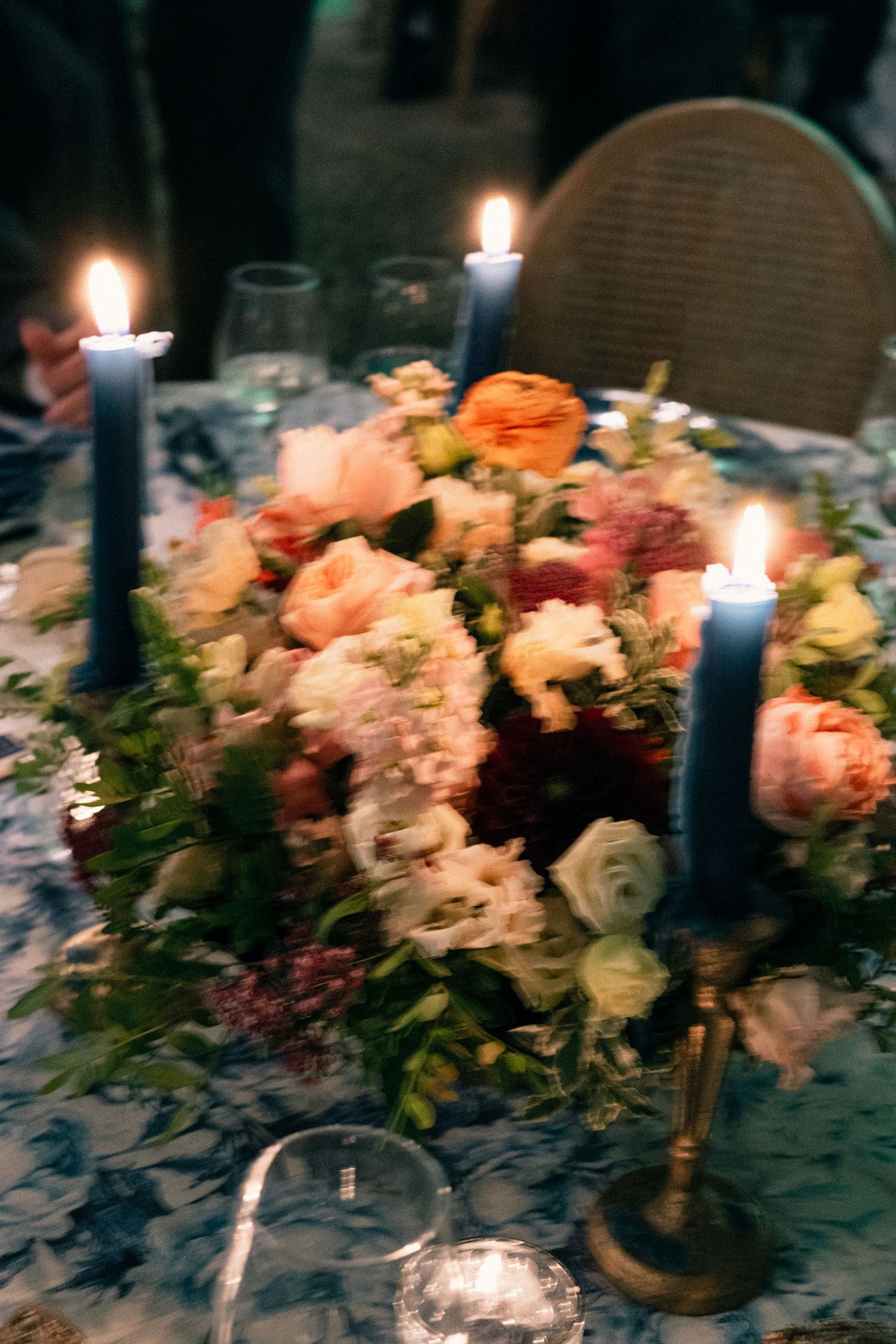Romantic table setting with lit candles and lush floral centerpiece featuring pink and white roses.
