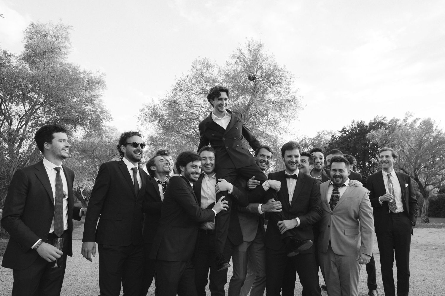 Group of formally dressed guests mingling outdoors at an elegant daytime event.