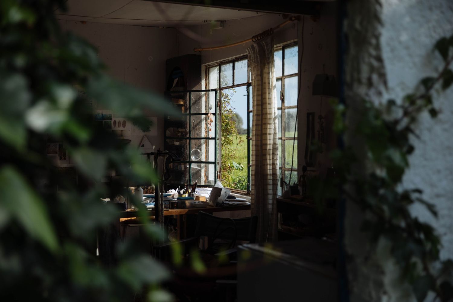 Dark interior room with sunlight streaming through large windows creating dramatic shadows.