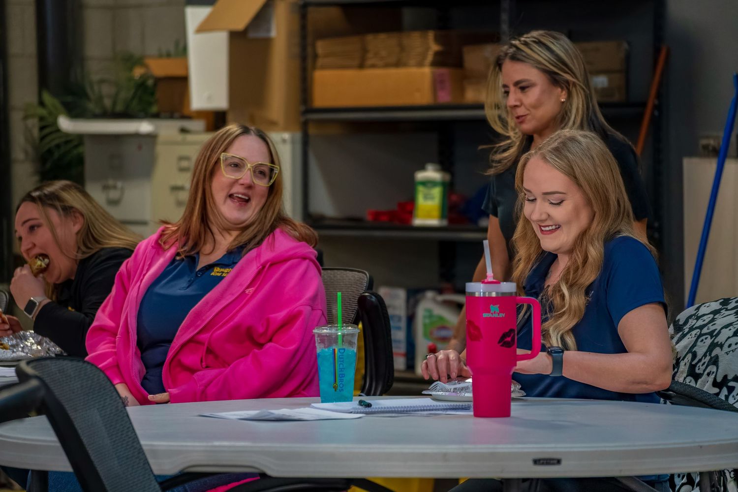 Group gathering at casual office celebration with bright pink attire.
