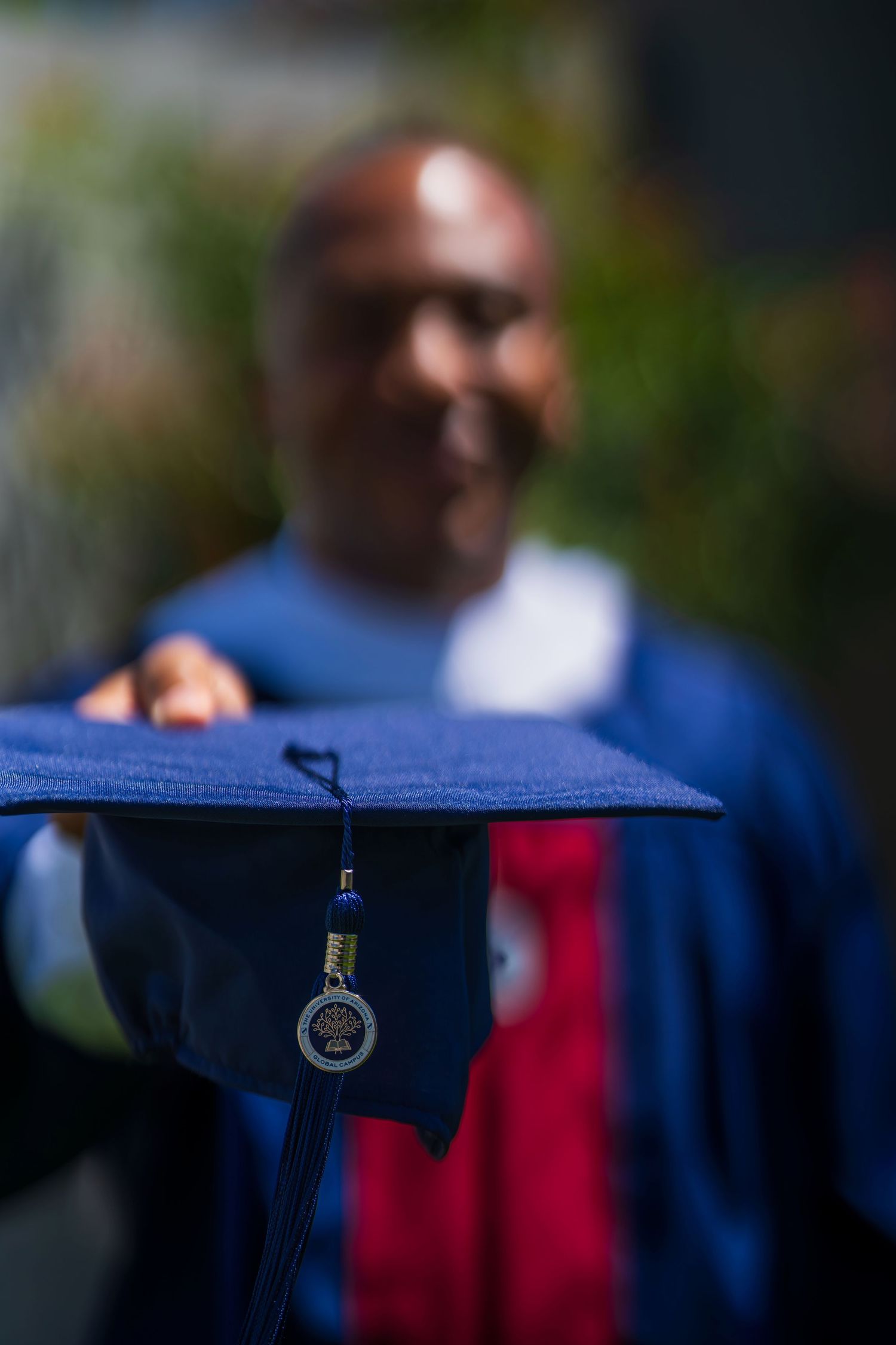 A graduation cap with tassel and medallion in focus against a blurred blue background.