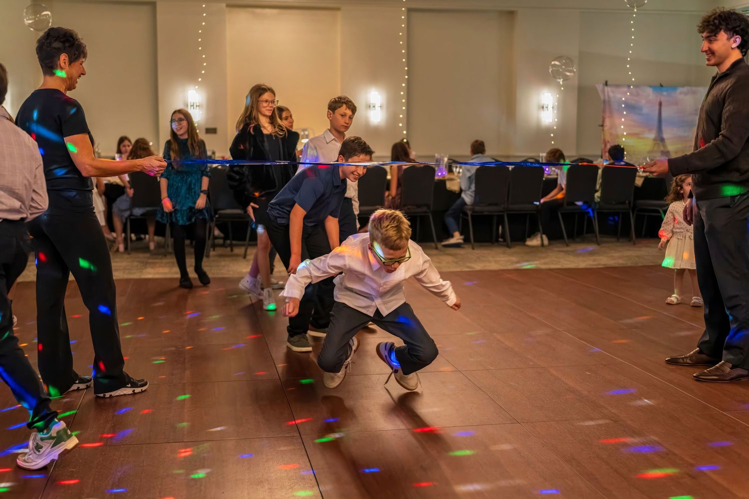 Kids dancing energetically at a colorful party venue with disco lights on the dance floor.