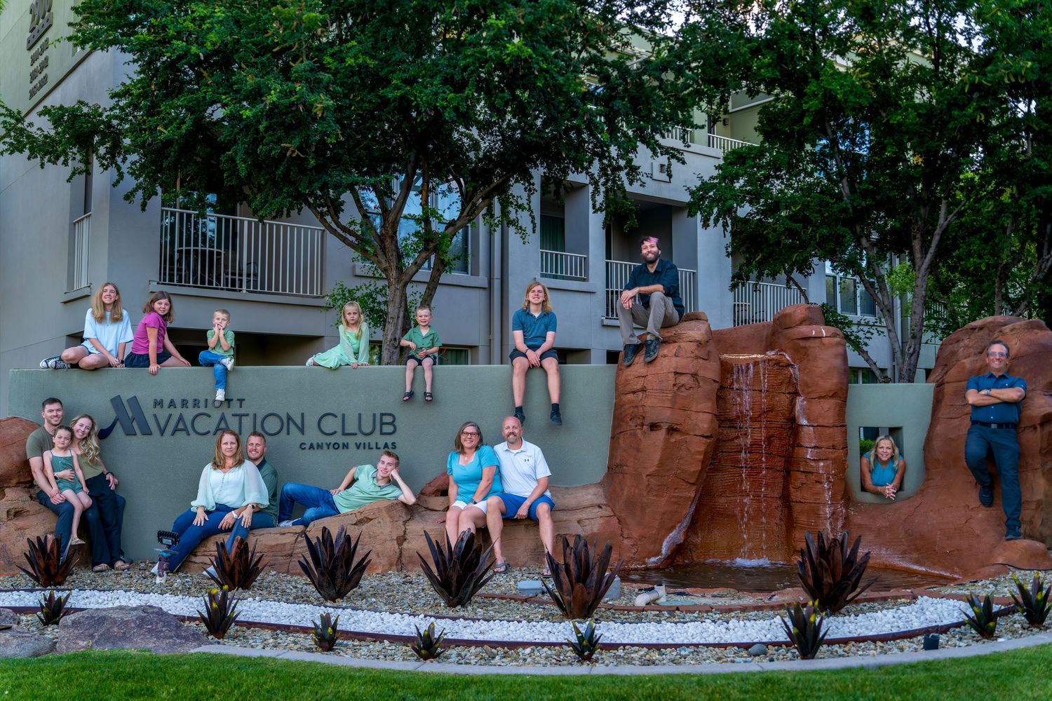 Large family group posing together outside a Marriott Vacation Club resort at dusk.