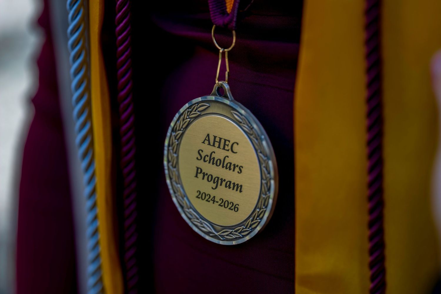 Close-up of an AHEC Scholars Program 2024-2026 medallion worn at a graduation ceremony.