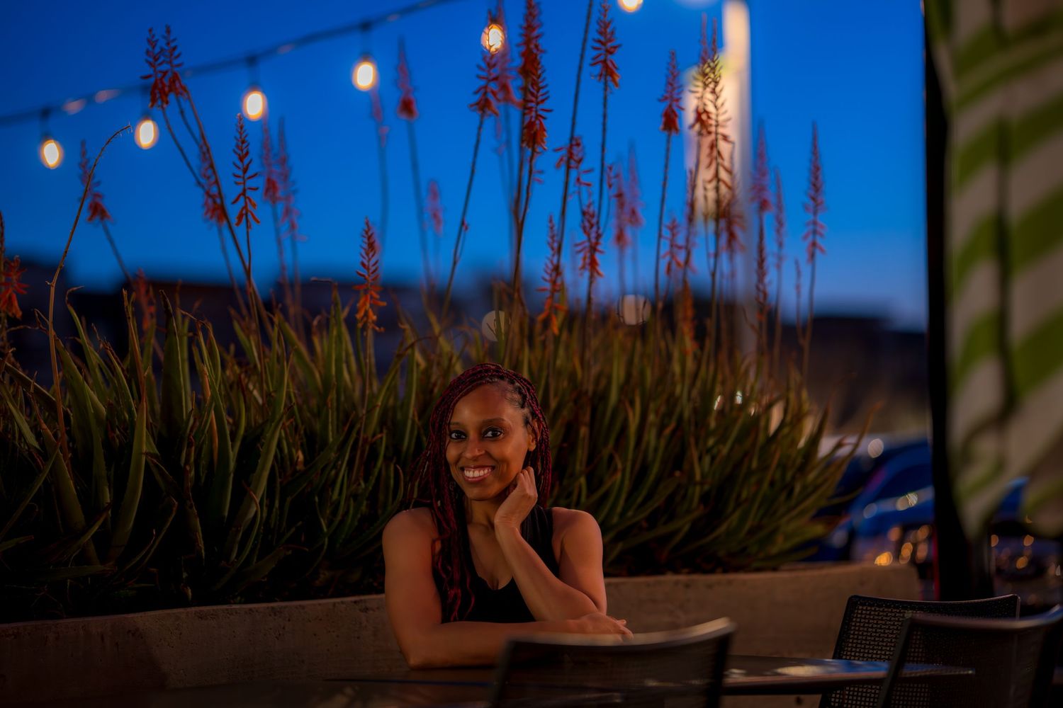 Outdoor evening portrait with string lights and ornamental grasses in background.