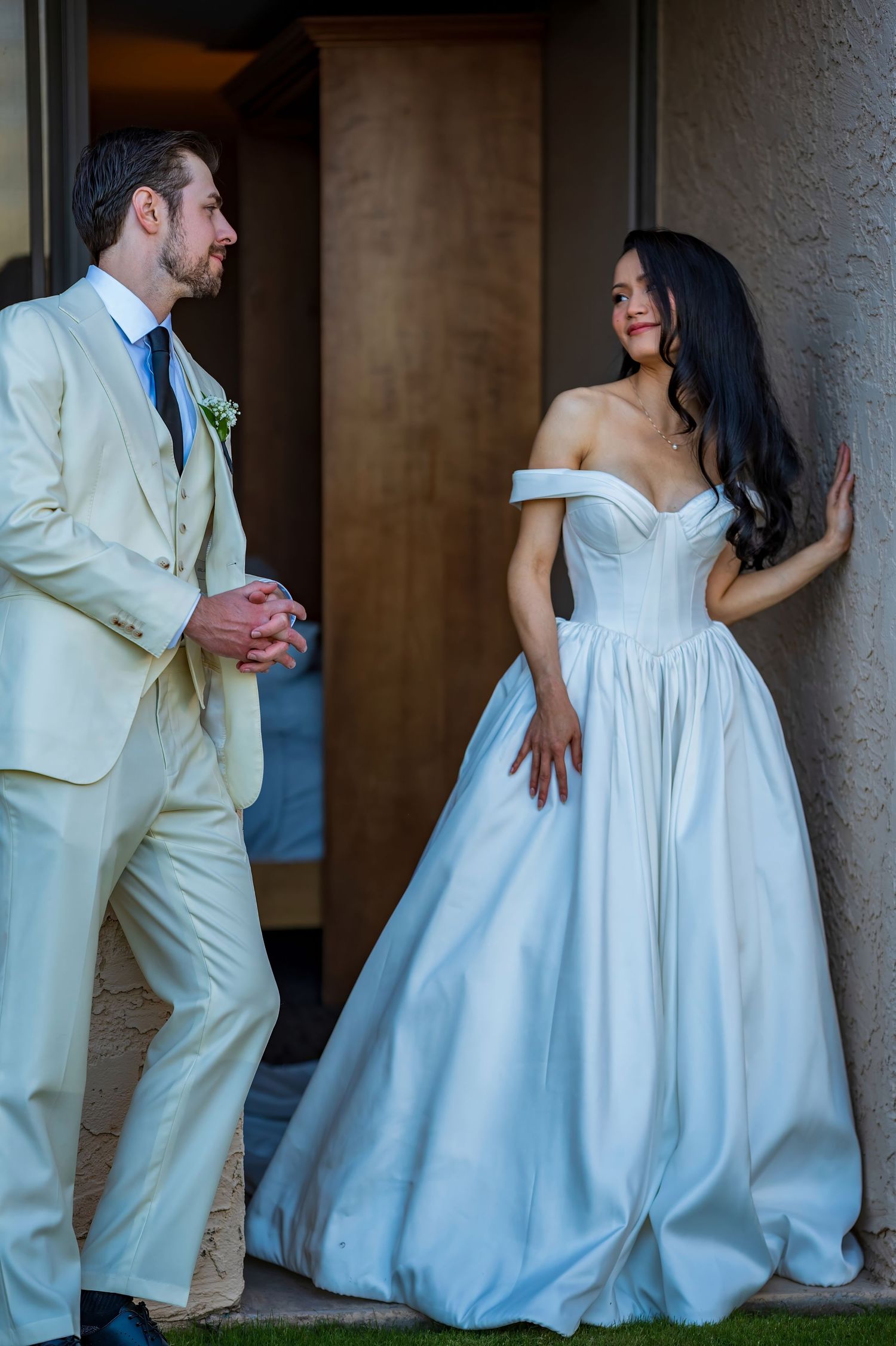 A playful wedding couple interacts in an outdoor setting wearing classic formal attire.