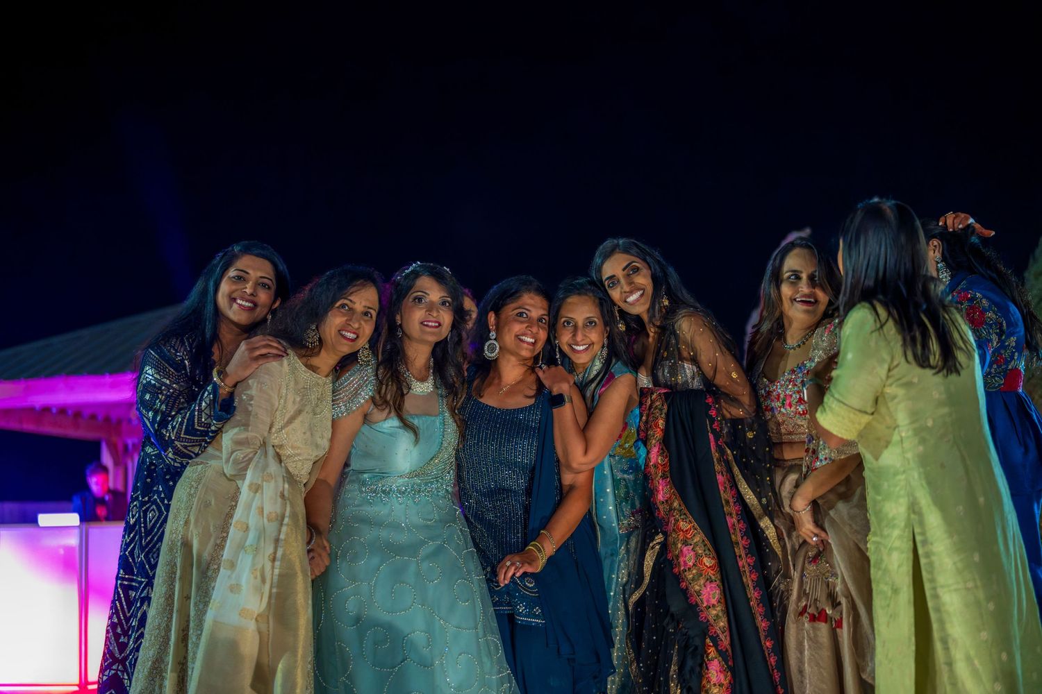 A group wearing traditional Indian attire poses together at a festive celebration.