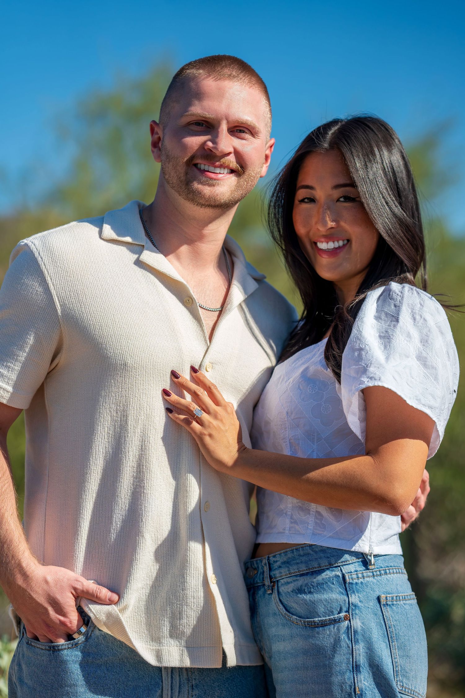 Couple in matching white tops and denim pose for photos in a desert setting with cacti.