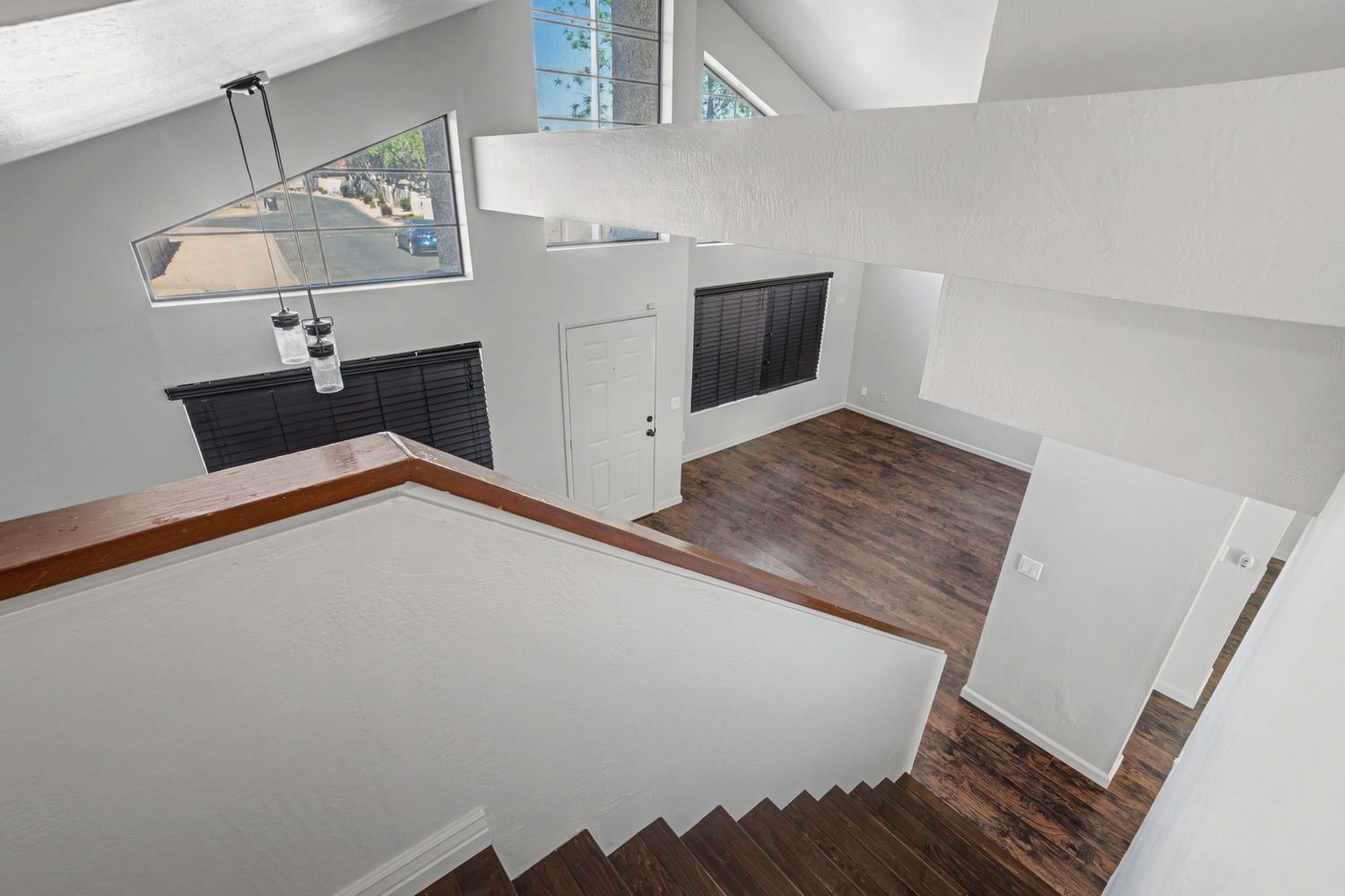 Overhead view of staircase leading to open living space with dark hardwood floors and vaulted ceilings.